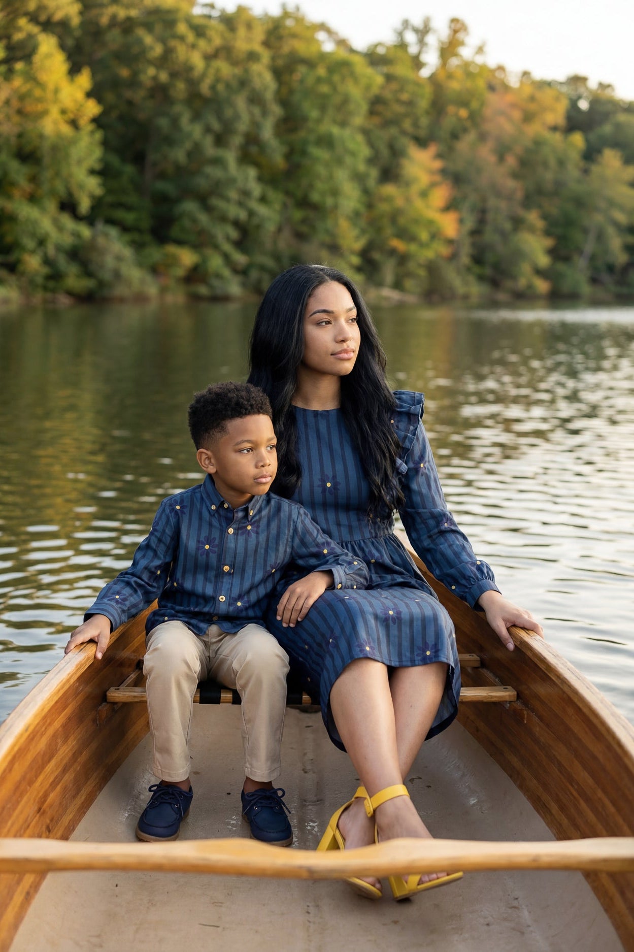 A picture of a mom and her boy in a canoe on a lake. The mom is wearing the Rae Top & The Boy is wearing the Boy's Button Shirt that is matching.