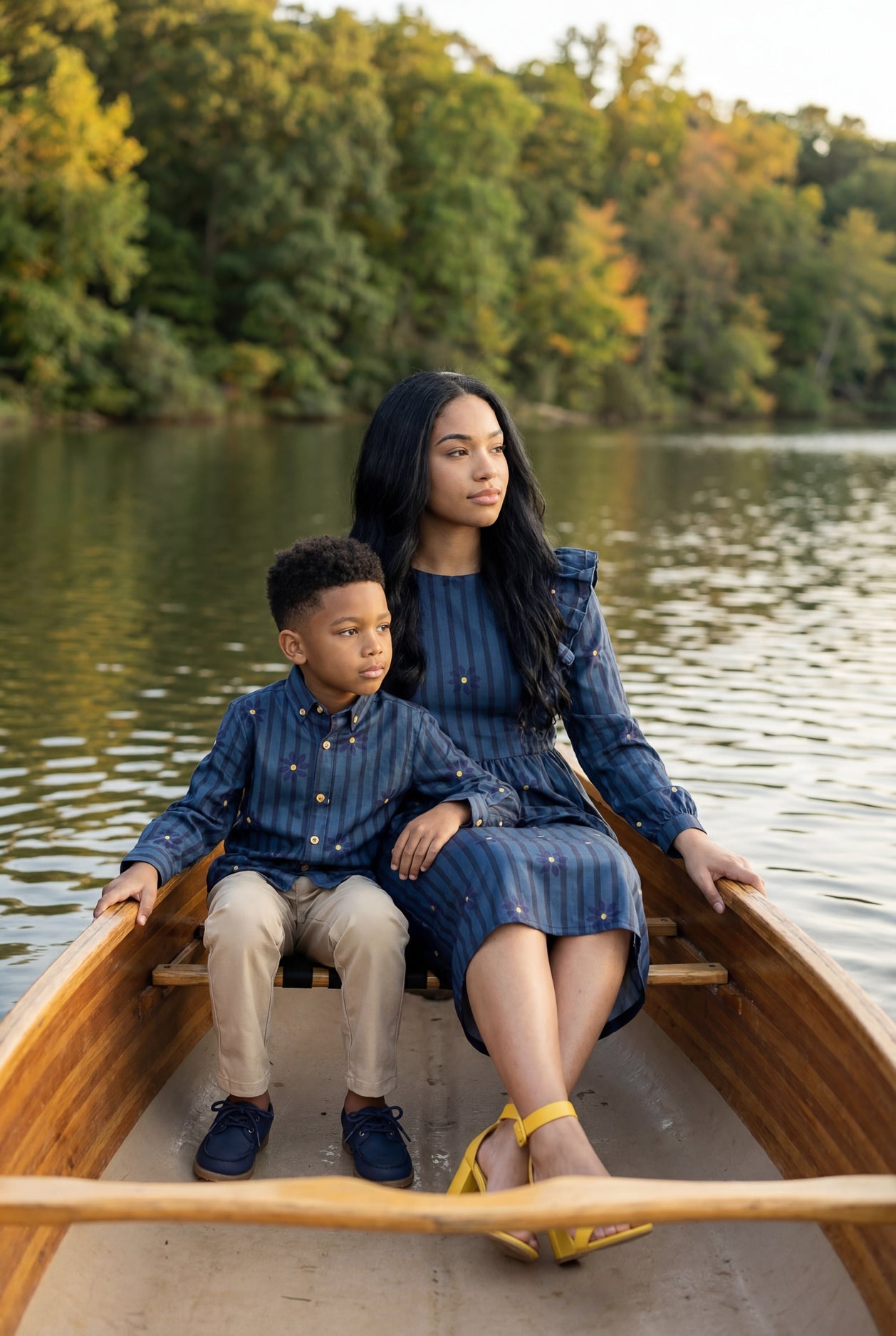 A picture of a mom and her boy in a canoe on a lake. The mom is wearing the Rae Top & The Boy is wearing the Boy's Button Shirt that is matching.
