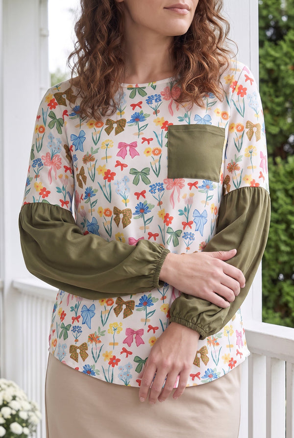 Nuggles® Gianna Top in Bouquet Toss, waist-up crop with arms crossed below the green chest pocket