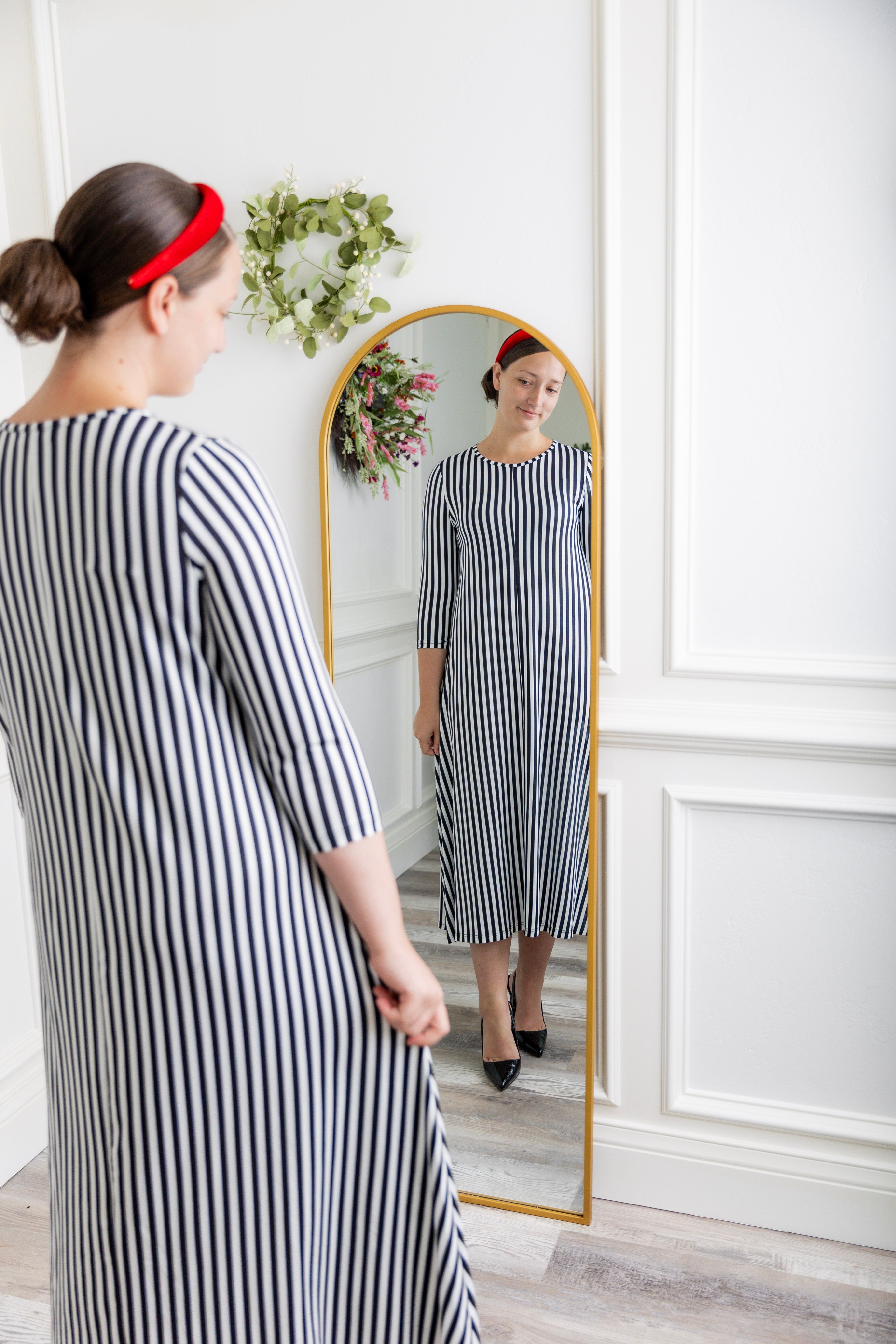 Women wearing a modest, midi length dress with 3/4 length sleeves in a black and white vertical stripe dress.