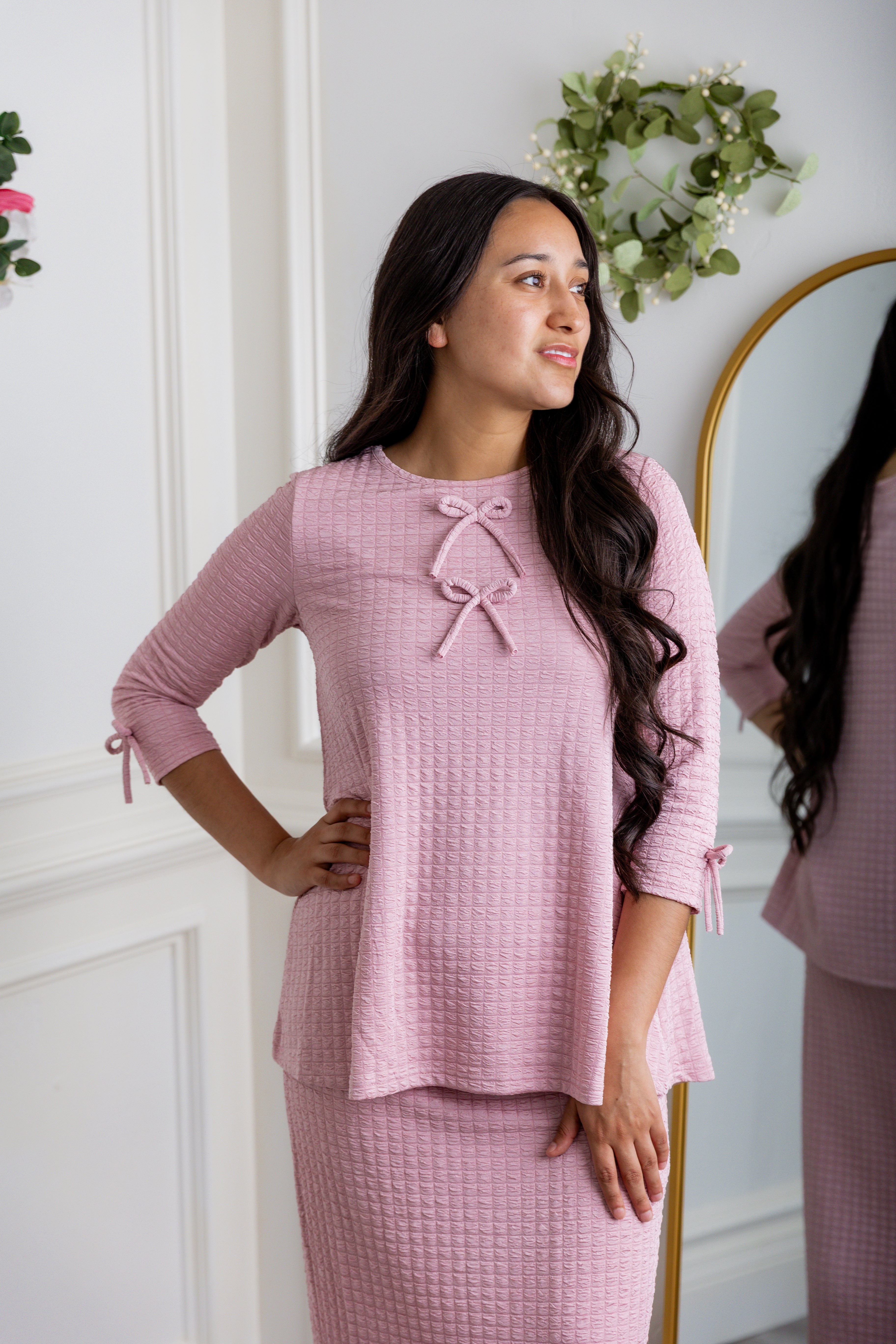 A woman wearing a blue and white detail top that has a modest neckline and 3/4 length sleeves.