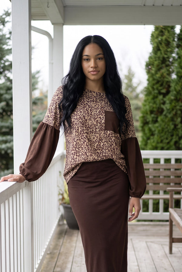 Nuggles® Gianna Top in Savanna, three-quarter length on a porch with a brown midi skirt, one hand on the rail