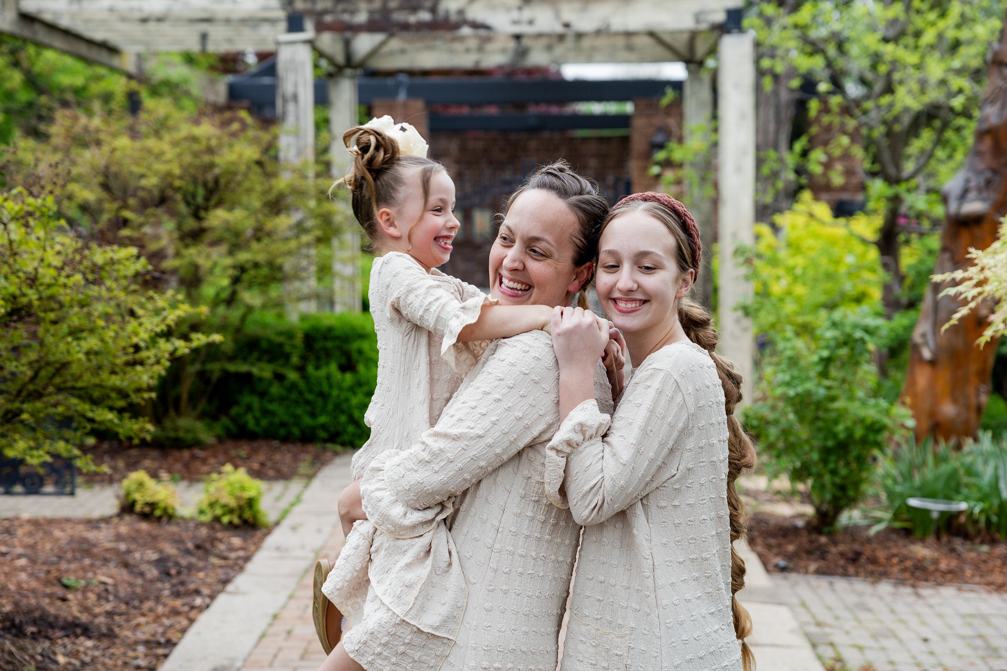 A Mom and daughters wearing a modest, midi length dress with 3/4 length sleeves.