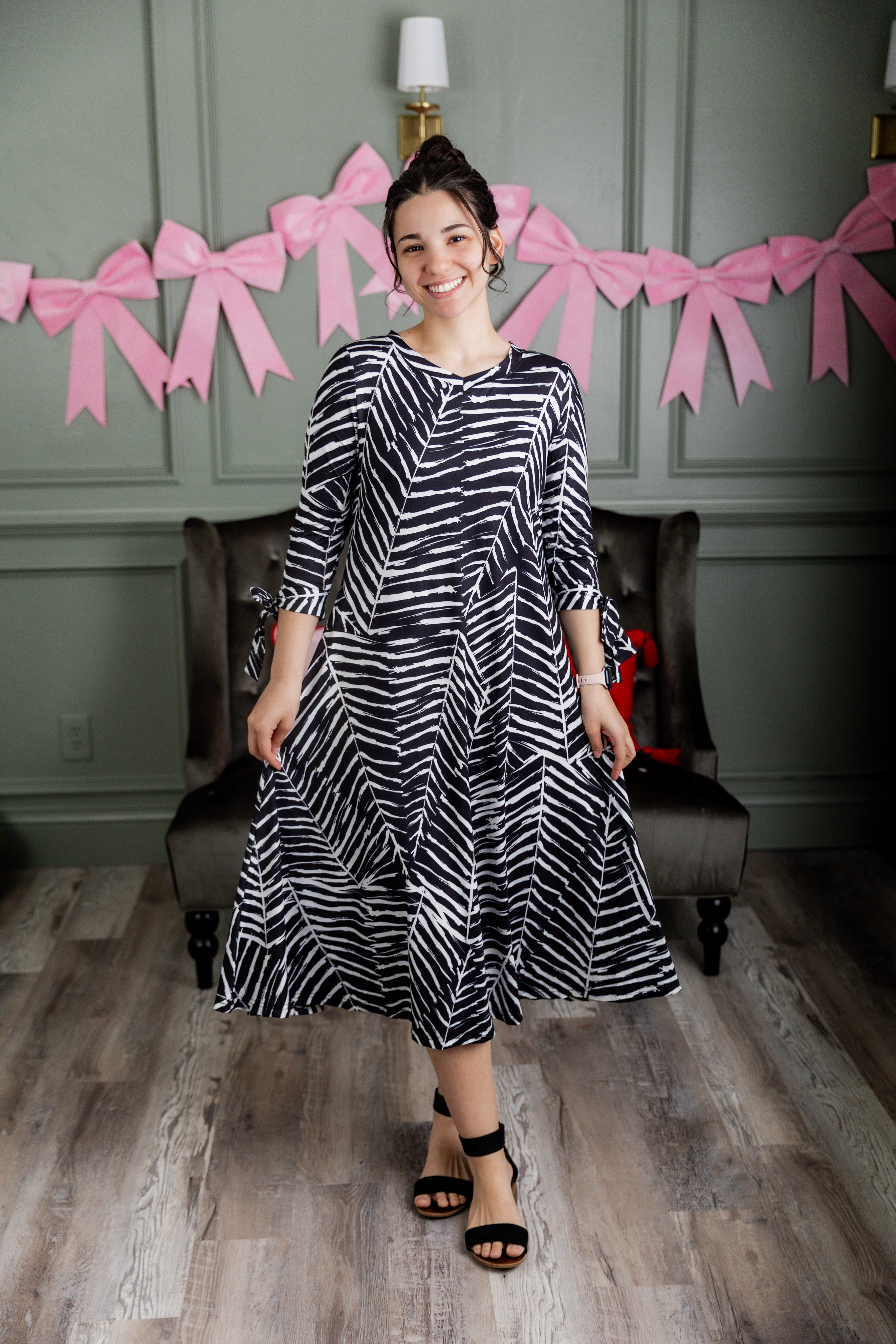 Model wearing Nuggles® Hazel Dress in Zebra Swirl black and white print with bow sleeves.