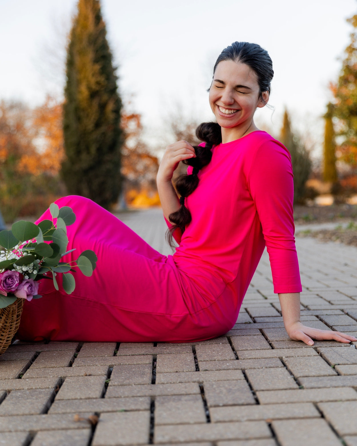 Woman wearing a bright pink dress in a minimalistic room with large windows.