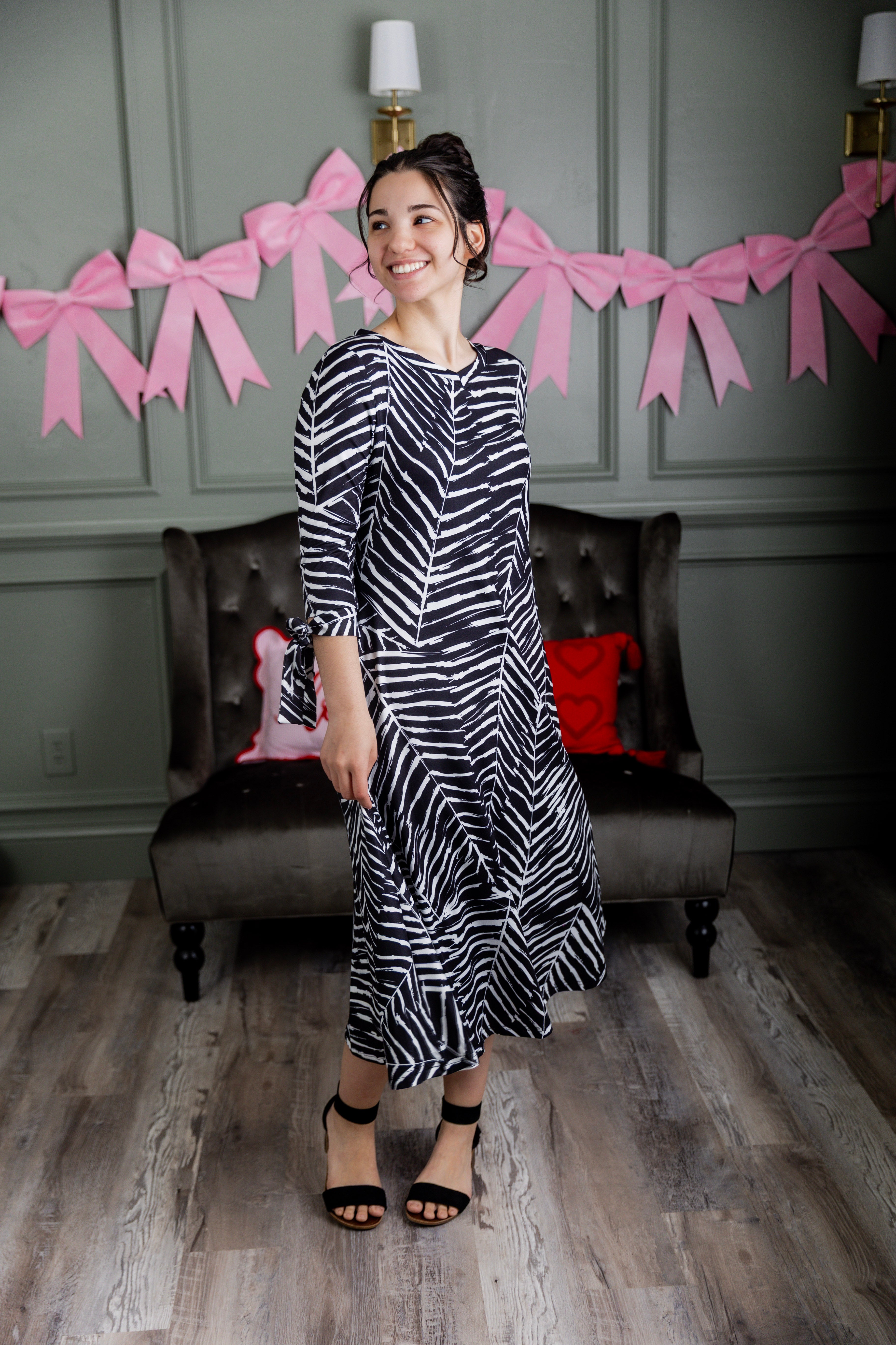 Model wearing Nuggles® Hazel Dress in Zebra Swirl black and white print with bow sleeves.
