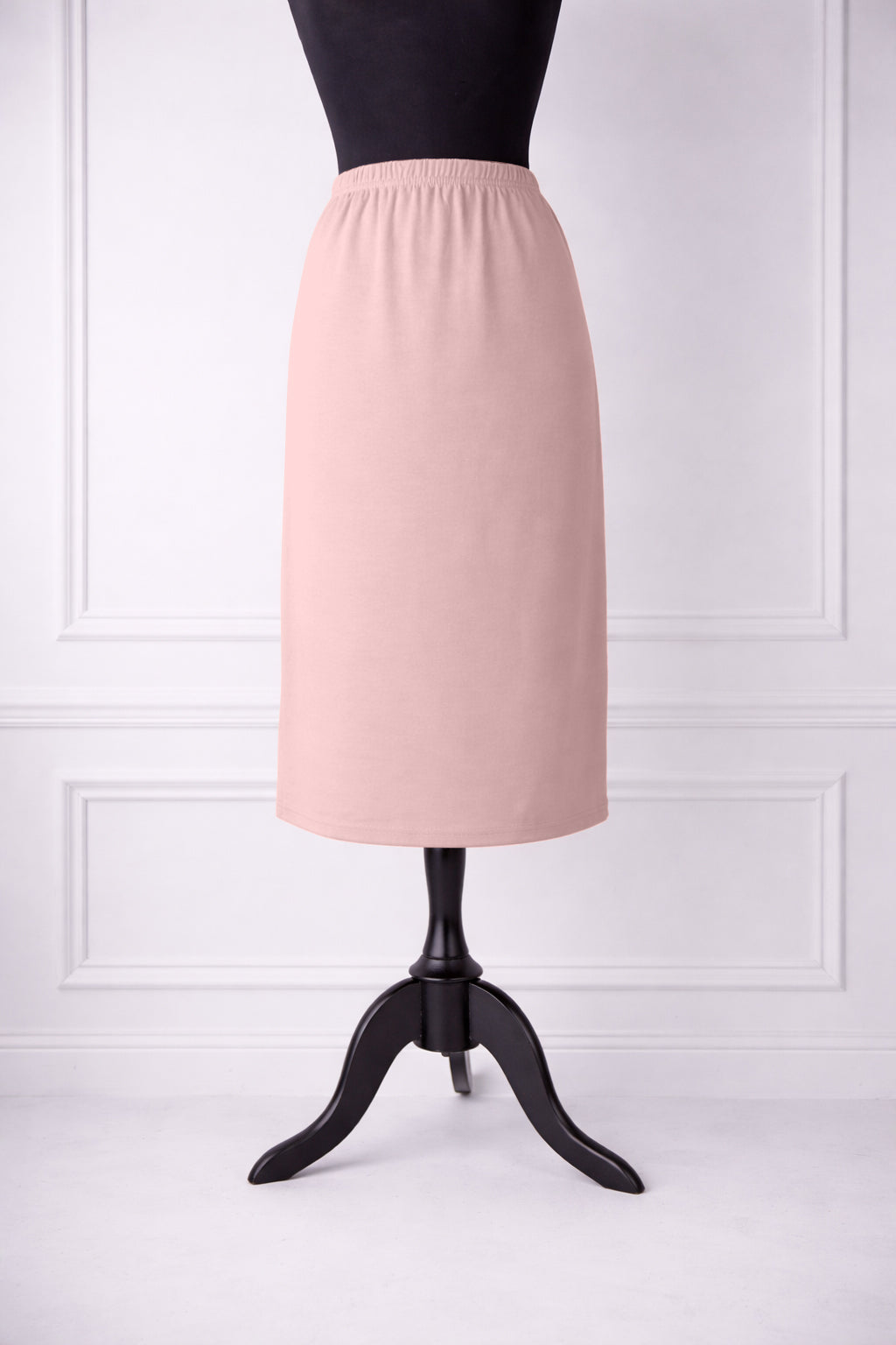 rose skirt on a mannequin against a white paneled wall.