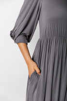 Modest Willow Solid Colors Dress by Nuggles® featuring a gathered waist, balloon sleeves, and side pockets; shown in various solid colors and angles for a stylish, comfortable everyday look.