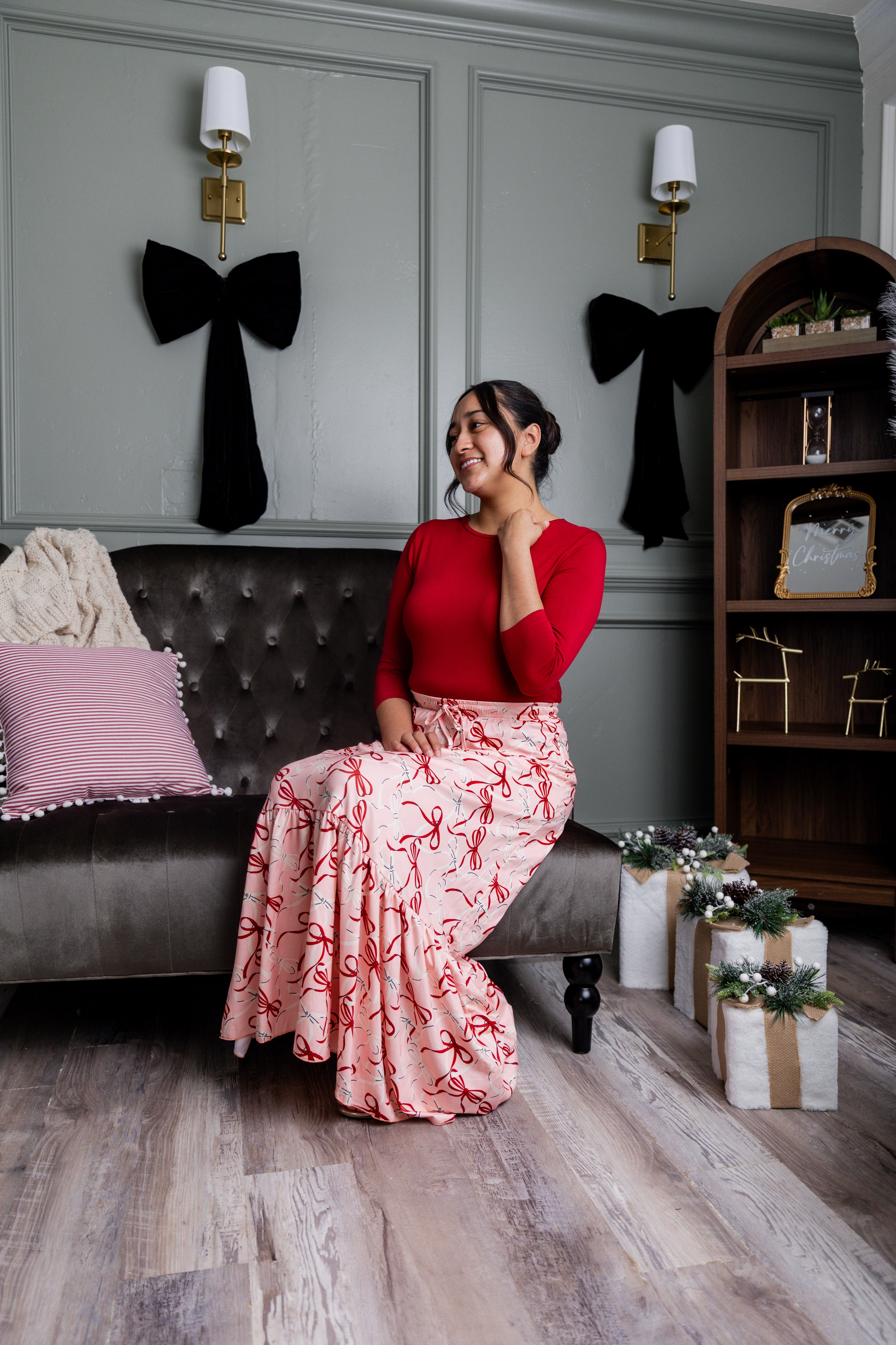 Model wearing the Nuggles® Sage Skirt in pink with red bow print, showcasing a tiered ruffle hem and soft, stretchy waistband.