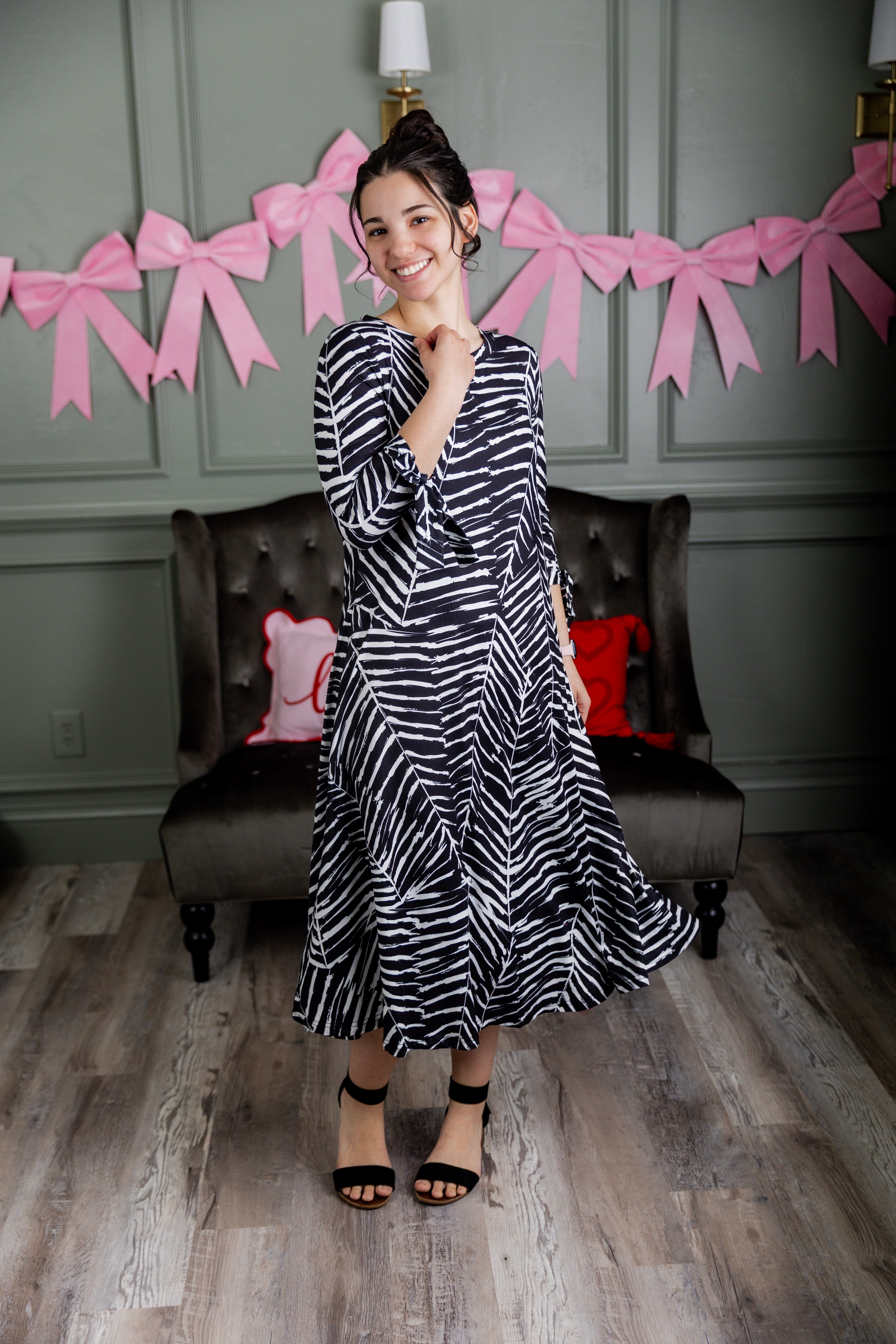 Model wearing Nuggles® Hazel Dress in Zebra Swirl black and white print with bow sleeves.