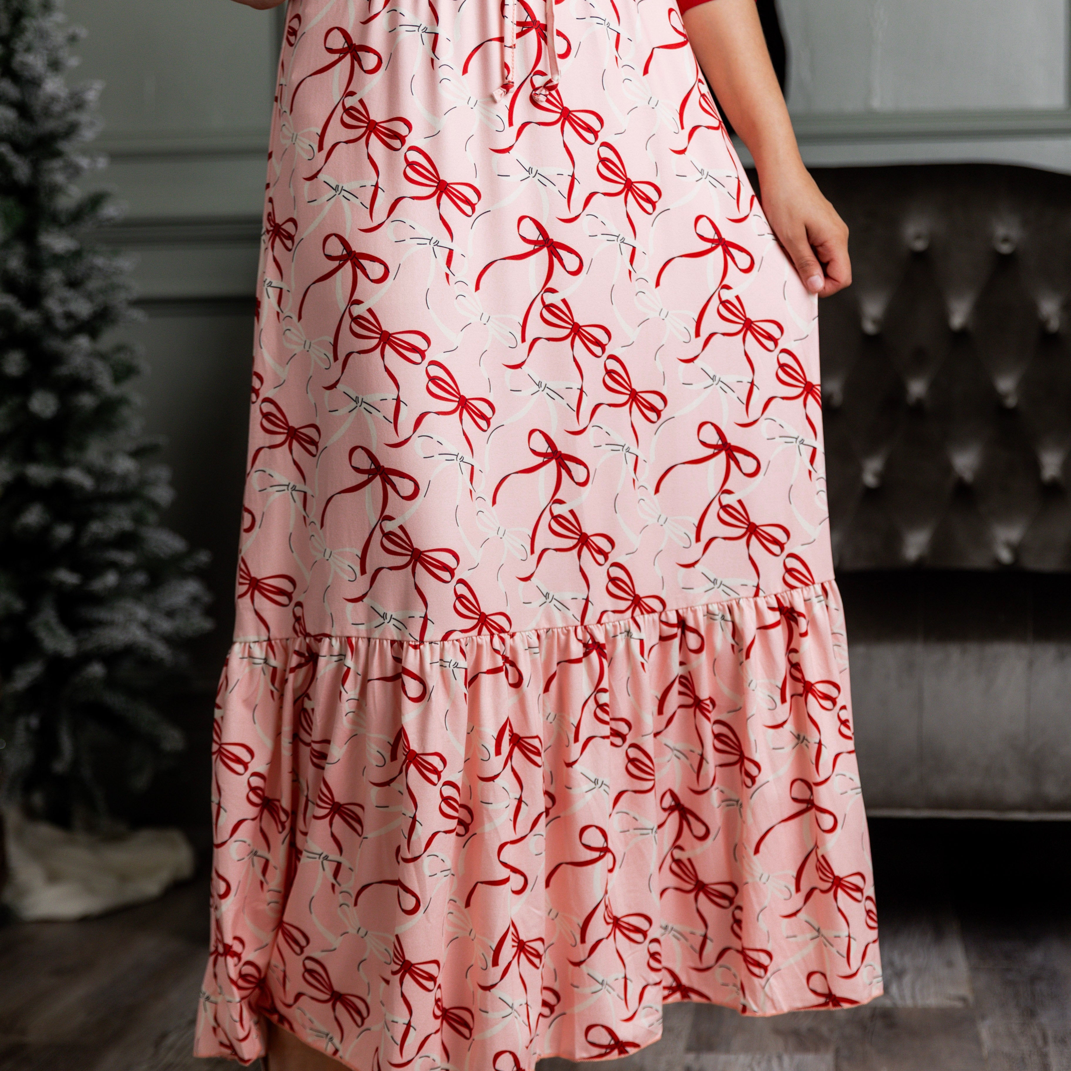 Model wearing the Nuggles® Sage Skirt in pink with red bow print, showcasing a tiered ruffle hem and soft, stretchy waistband.