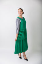 model wearing a shamrock tiered midi dress over a black and white striped sleeve top.