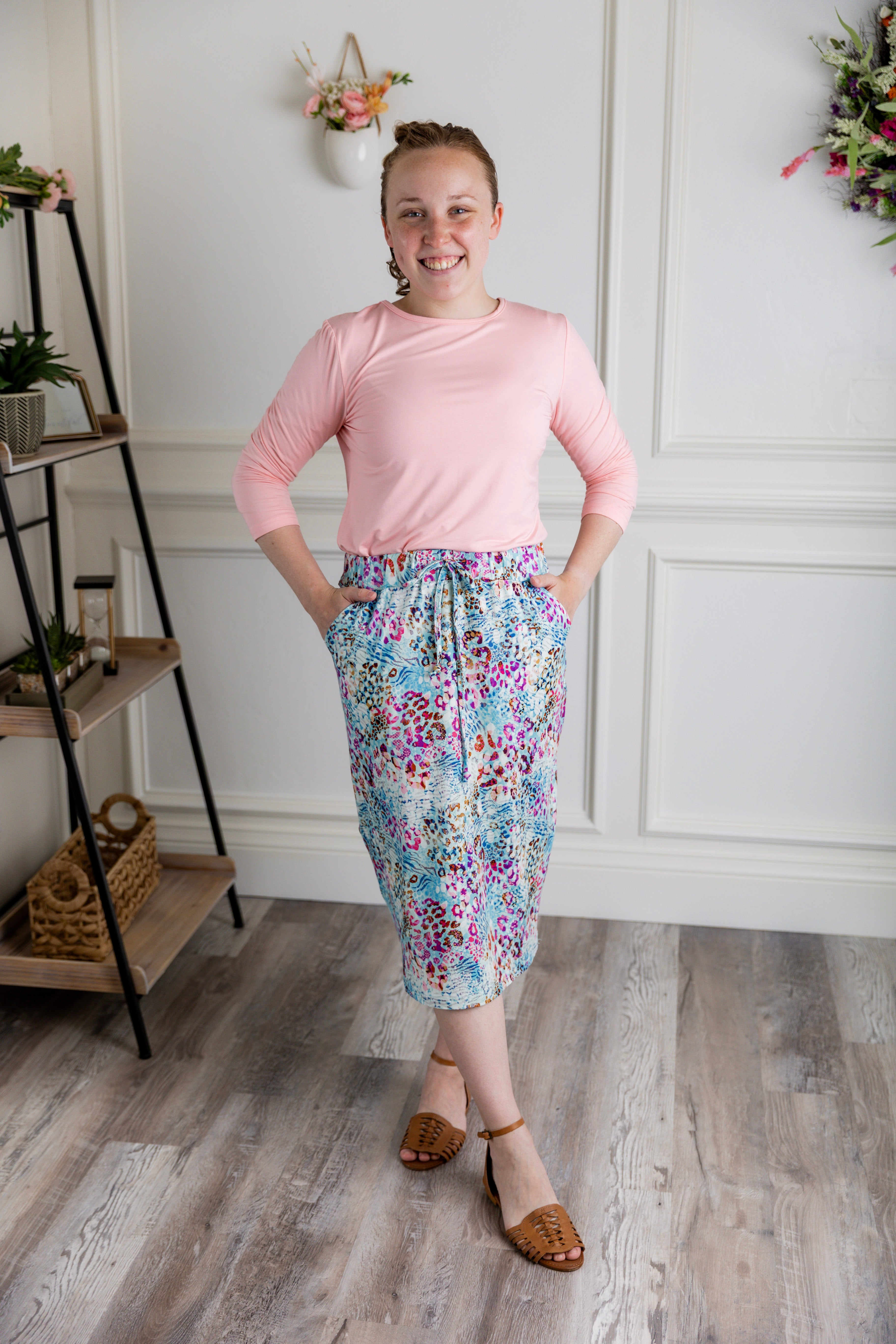 Woman wearing a 27-inch modest midi skirt with multicolor animal print, drawstring waist, and pockets.