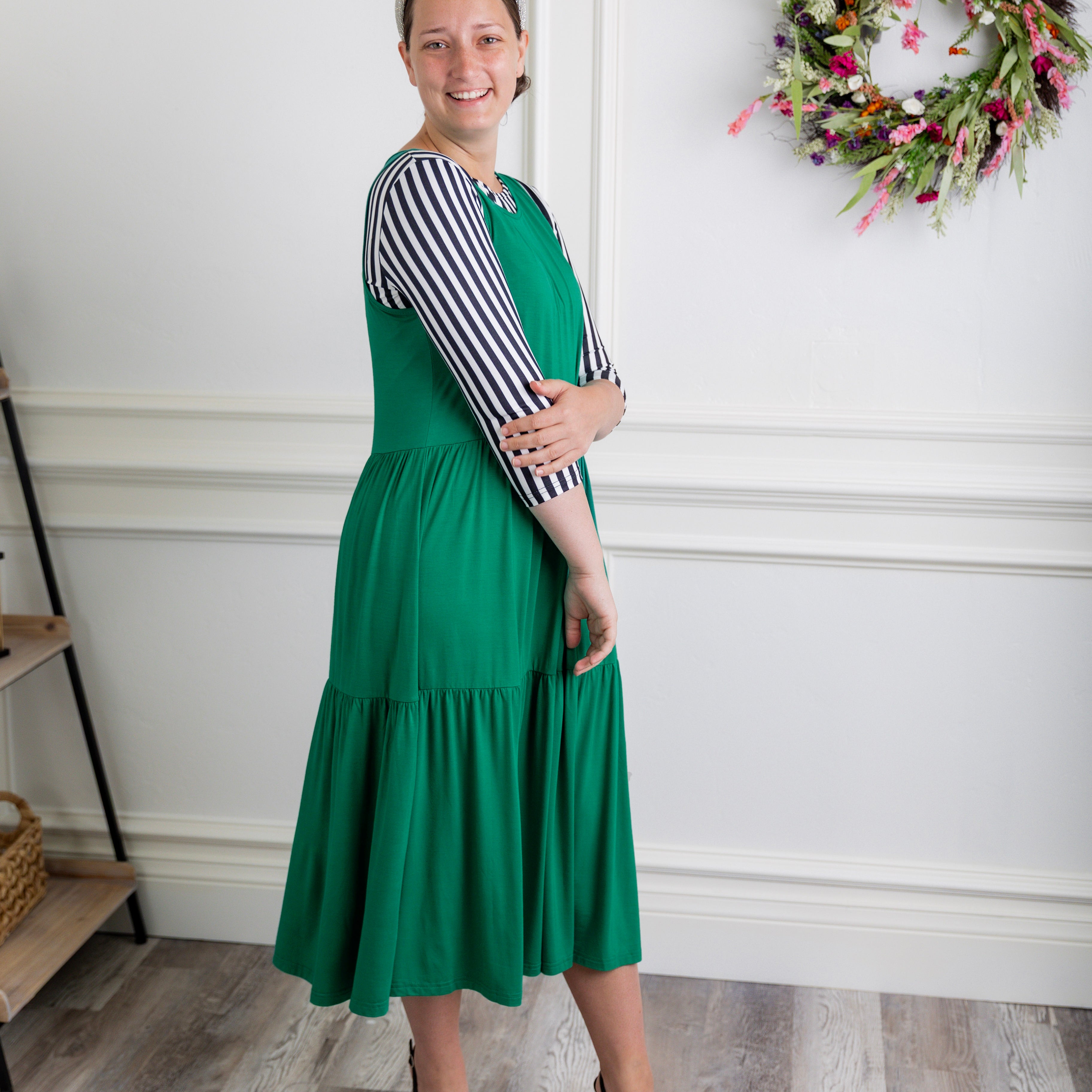 model wearing a shamrock tiered midi dress over a black and white striped sleeve top.