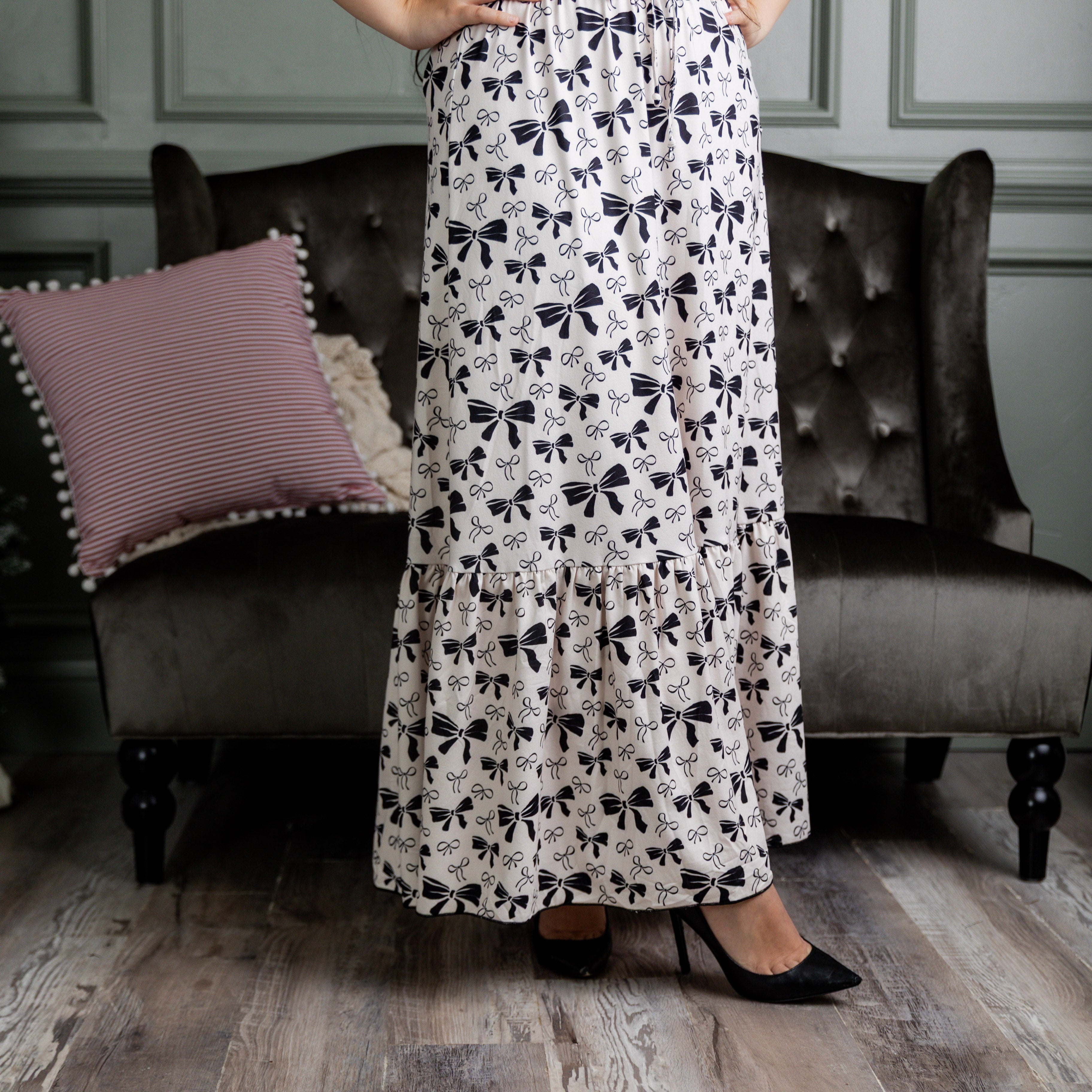 Model wearing the Nuggles® Sage Skirt in white with black bow print, featuring a gathered tiered hem and adjustable drawstring waist.