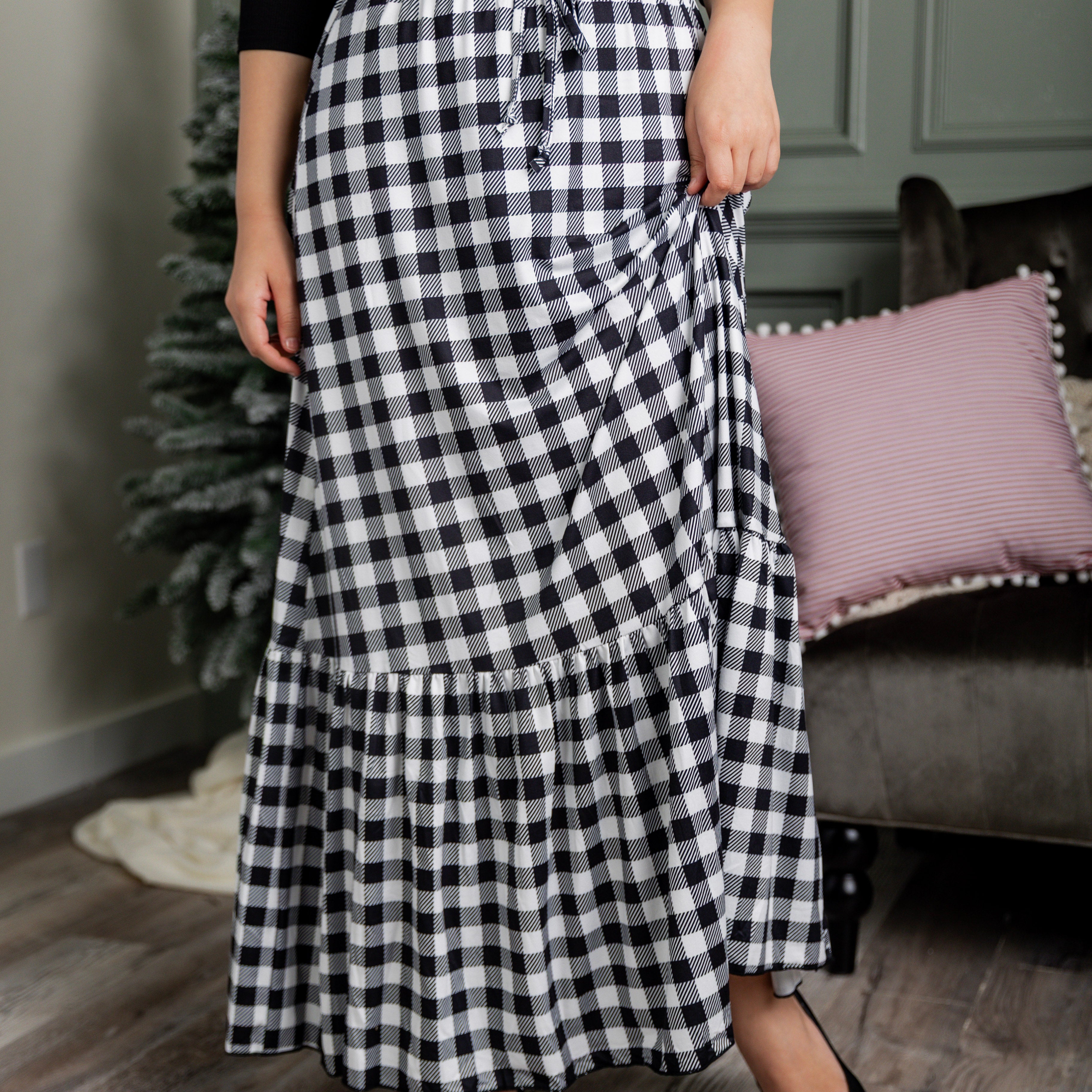 Model wearing the Nuggles® Sage Skirt in black and white gingham, featuring a tiered ruffle hem and drawstring waist.