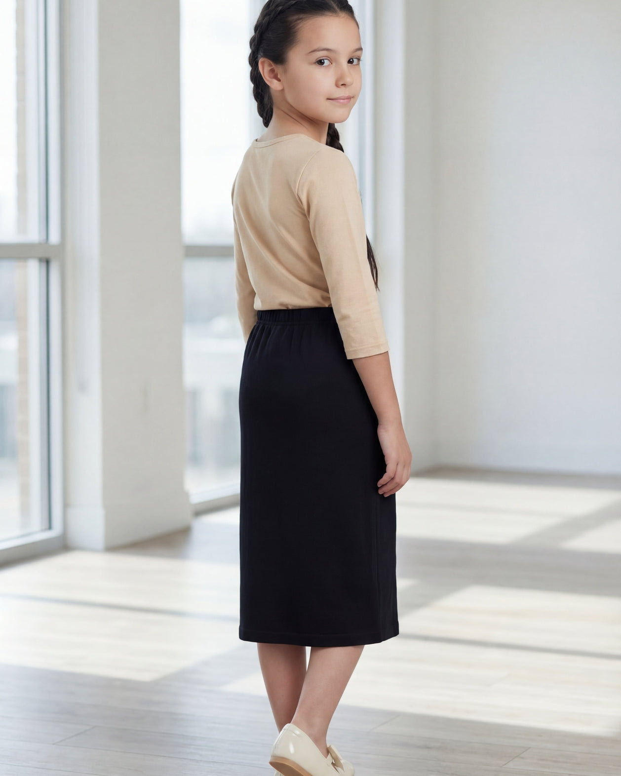 Model wearing the Nuggles® Girls' Classic Midi Skirt in Black