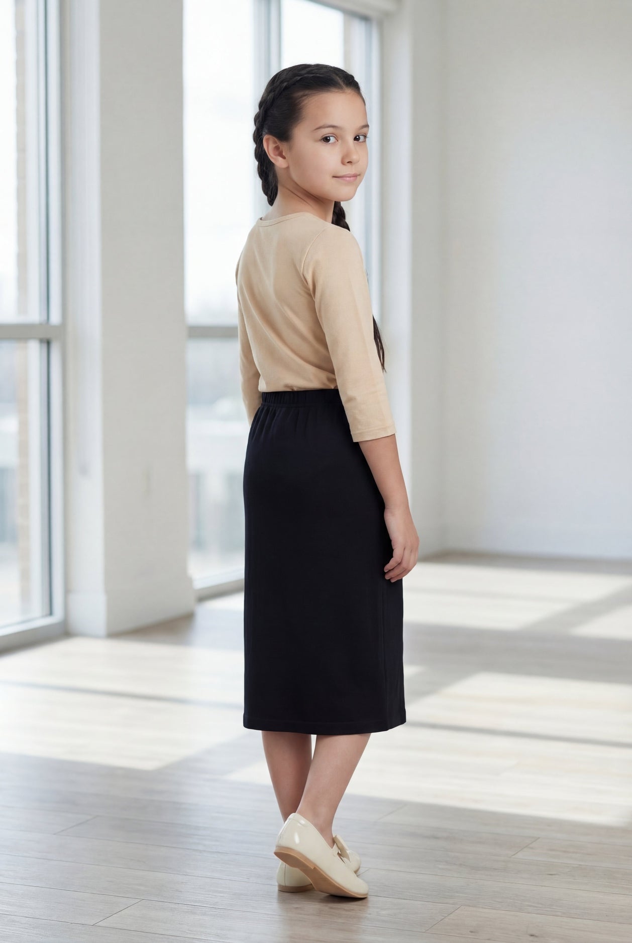 Model wearing the Nuggles® Girls' Classic Midi Skirt in Black