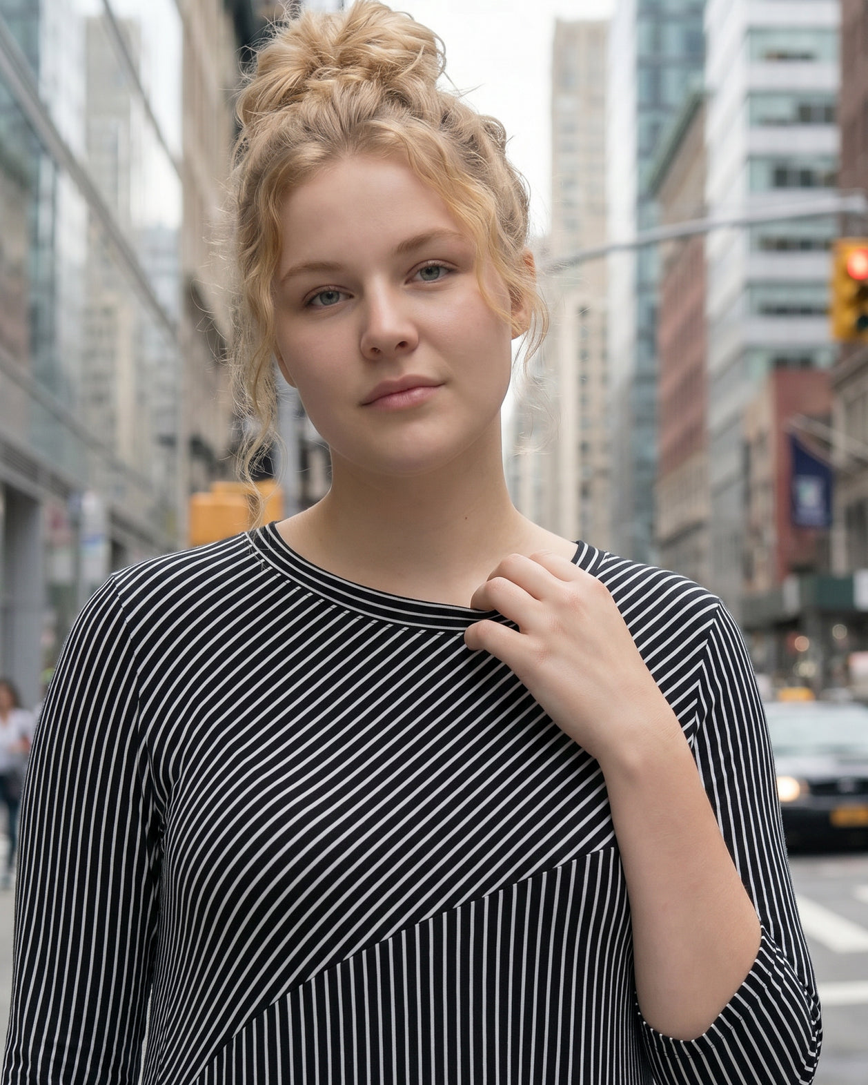 Woman in a black and white striped dress standing on a city street.