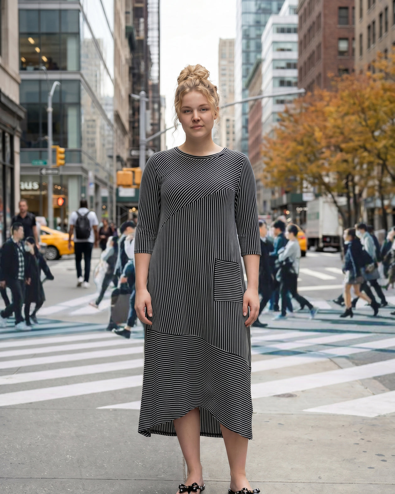 Woman in a black and white striped dress standing on a city street.