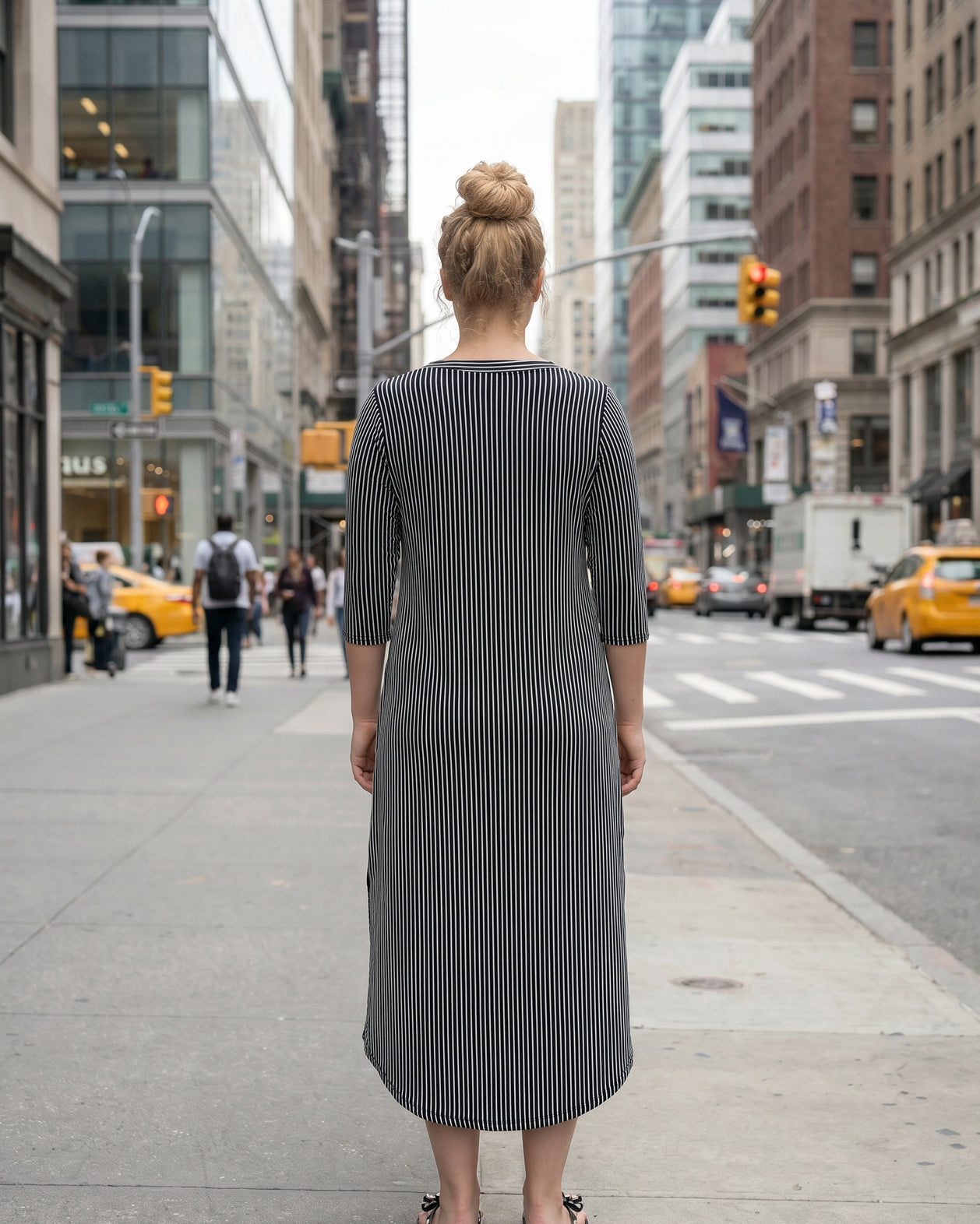 Woman in a black and white striped dress standing on a city street.