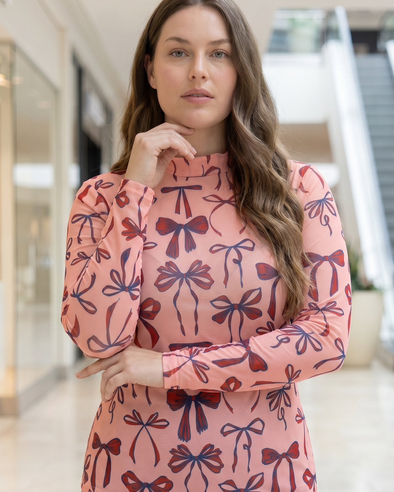A picture of a women wearing a pink, red, and blue bow print mesh tee.