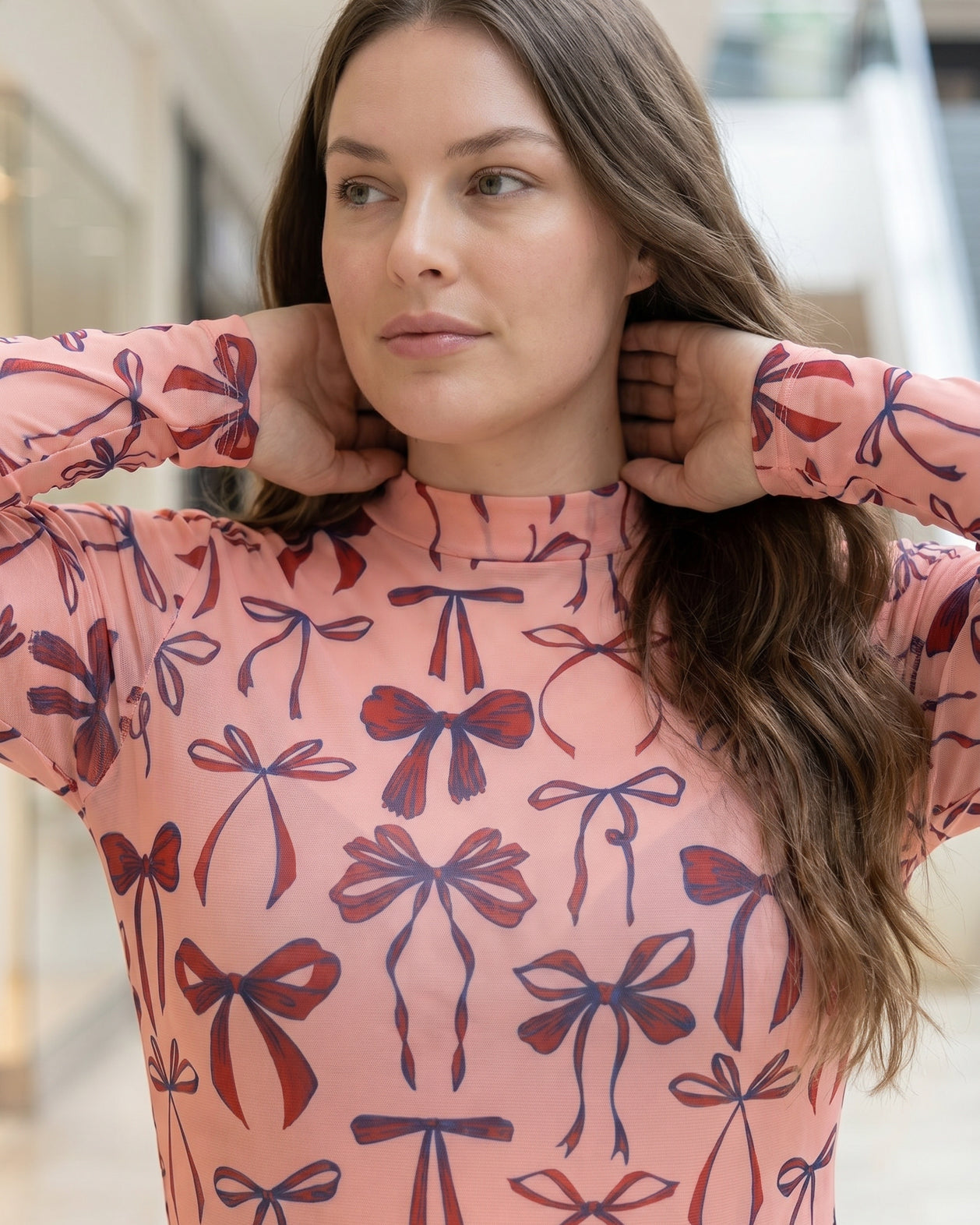 A picture of a women wearing a pink, red, and blue bow print mesh tee.