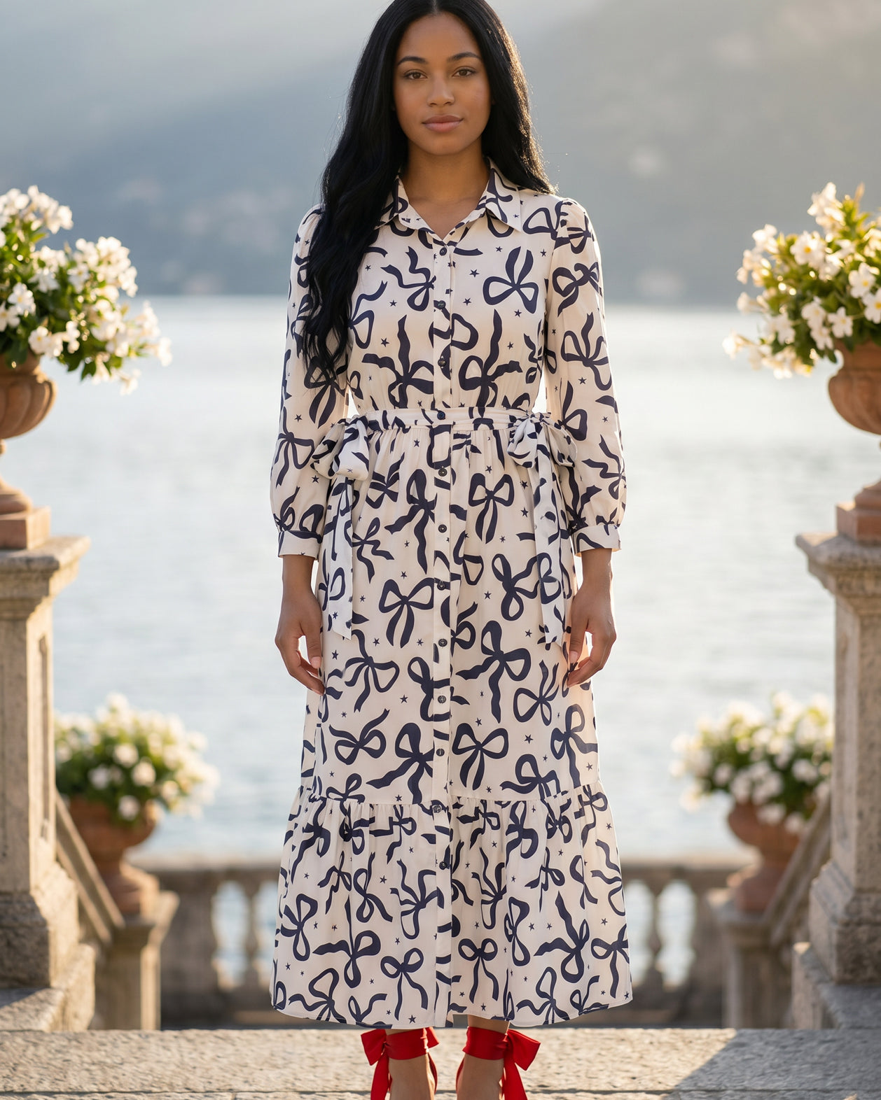 A picture of a young women wearing the Leila Dress in a bow print with a soft ivory base.