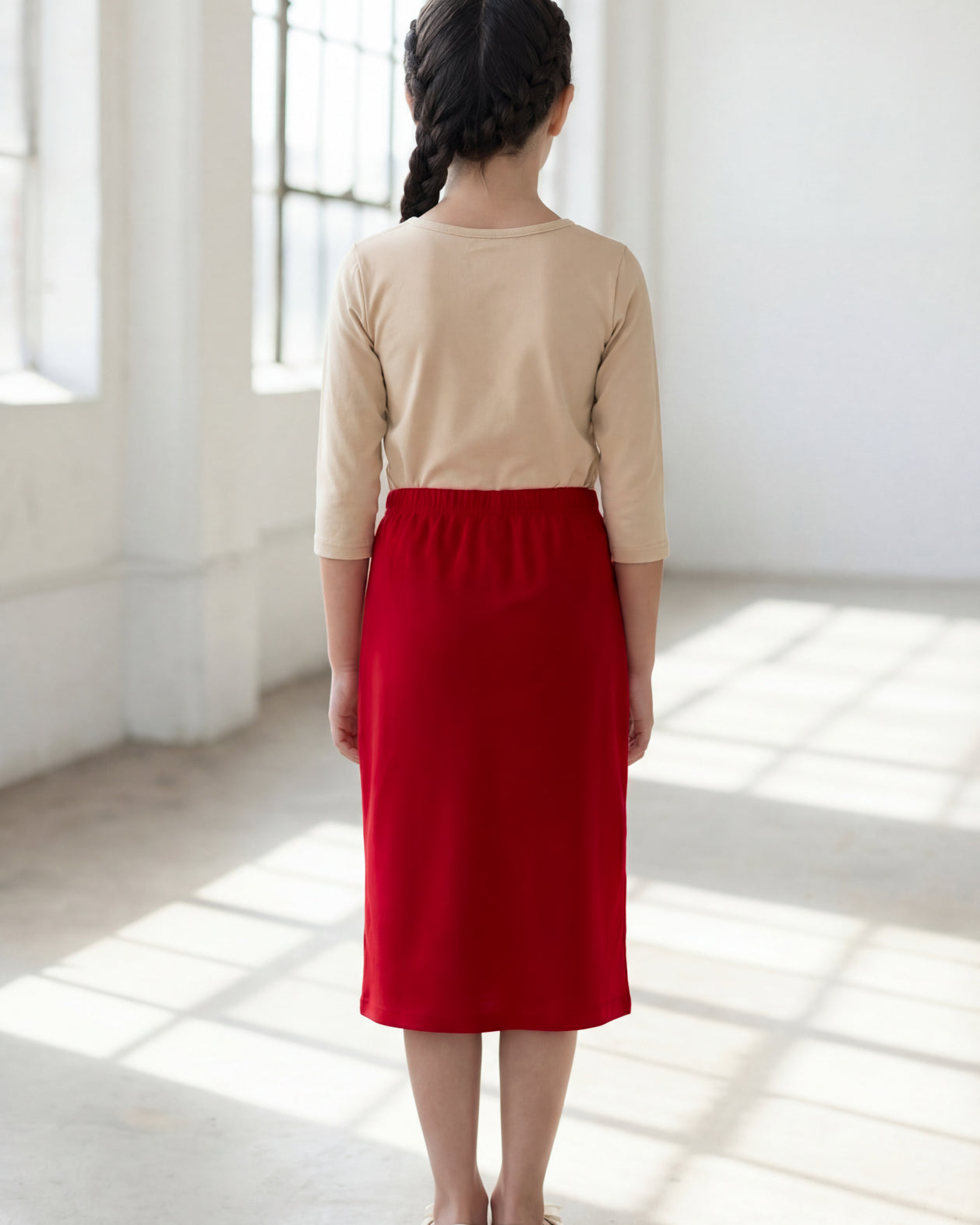 Model wearing the Nuggles® Girls' Classic Midi Skirt in Brick Red