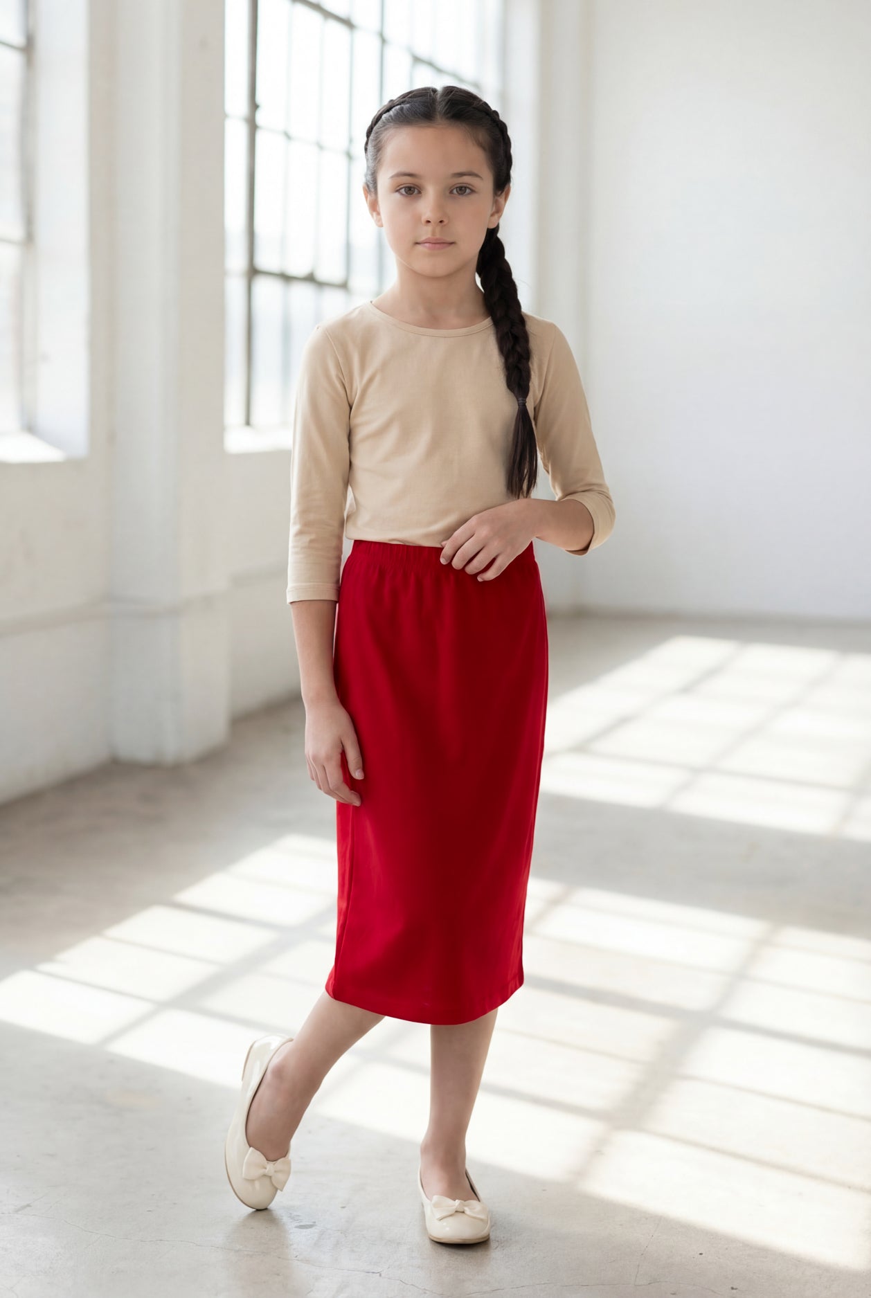 Girl wearing Nuggles® Modest Midi Skirt in Brick Red with a nude essential 3/4 tee in a sun light loft