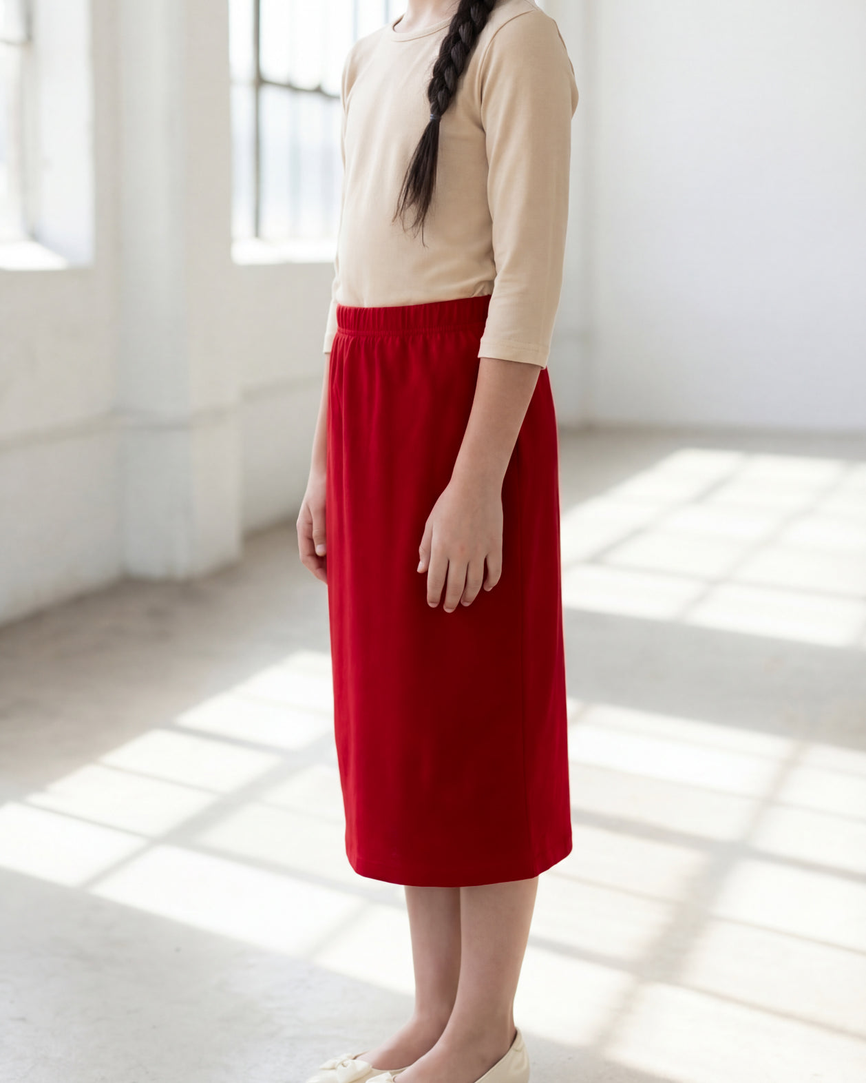 Model wearing the Nuggles® Girls' Classic Midi Skirt in Brick Red