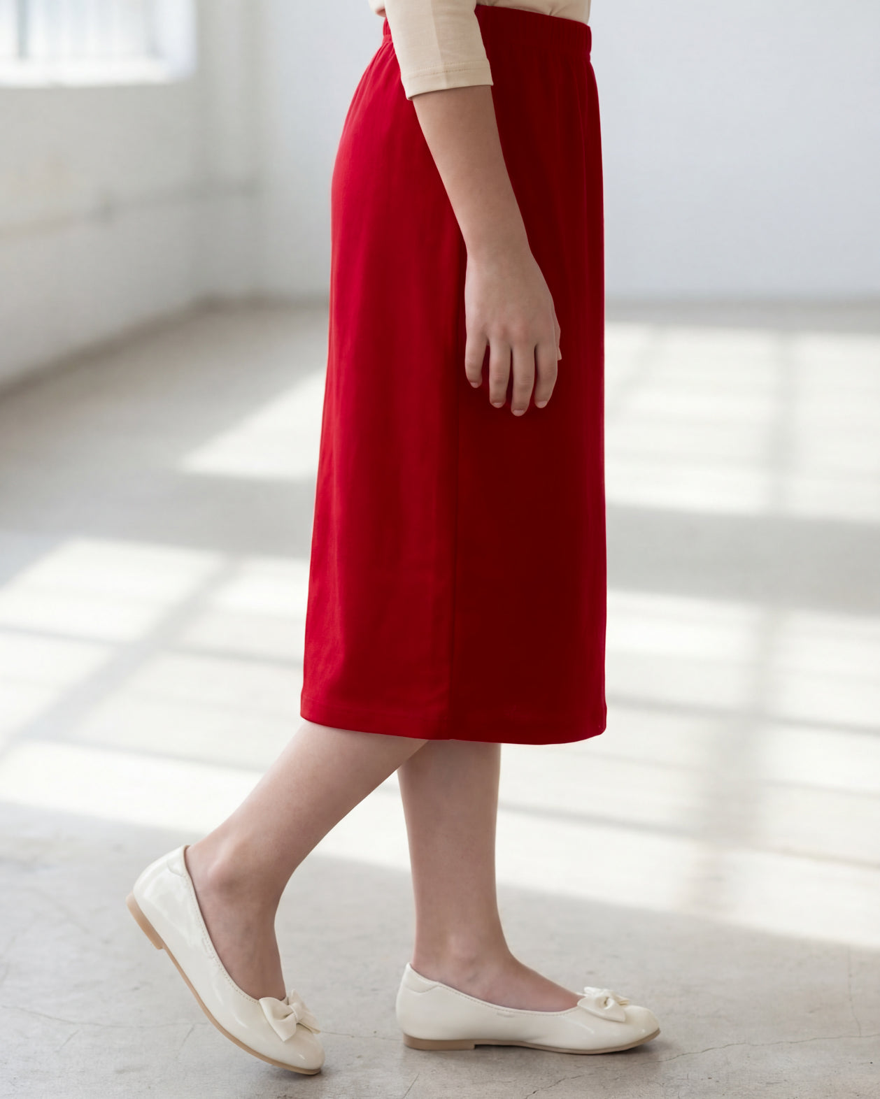 Model wearing the Nuggles® Girls' Classic Midi Skirt in Brick Red