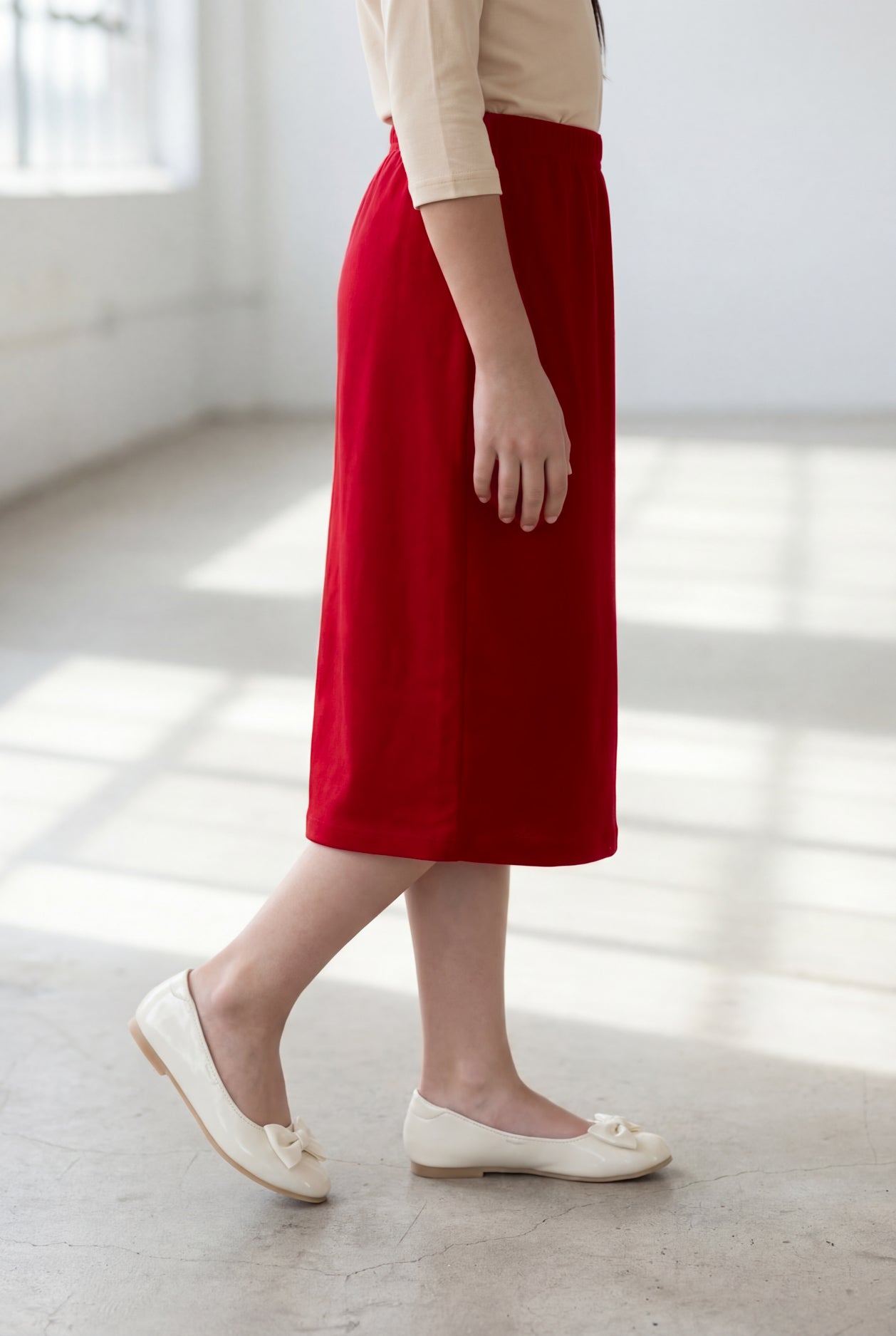 Girl wearing Nuggles® Modest Midi Skirt in Brick Red with a nude essential 3/4 tee in a sun light loft