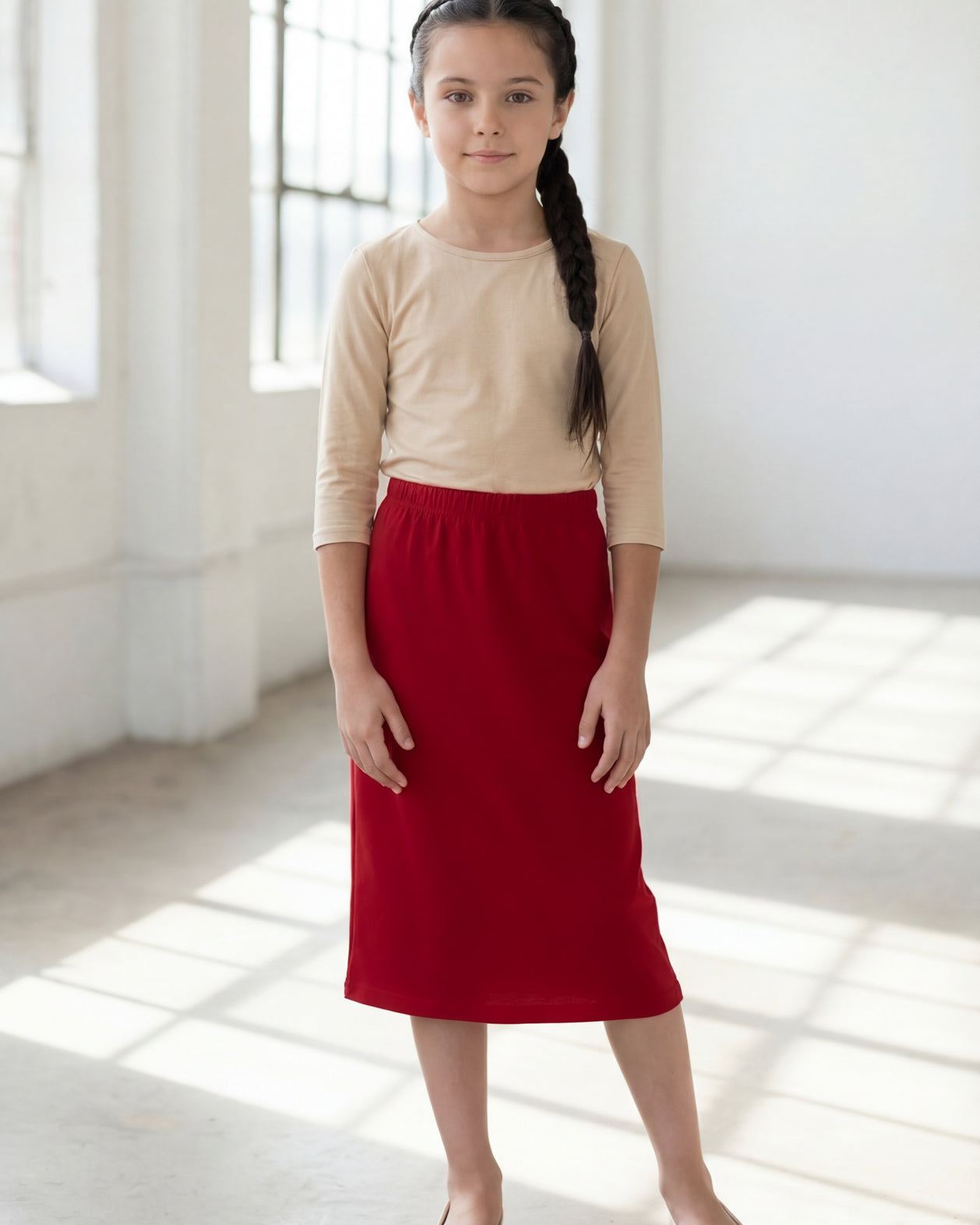 Model wearing the Nuggles® Girls' Classic Midi Skirt in Brick Red