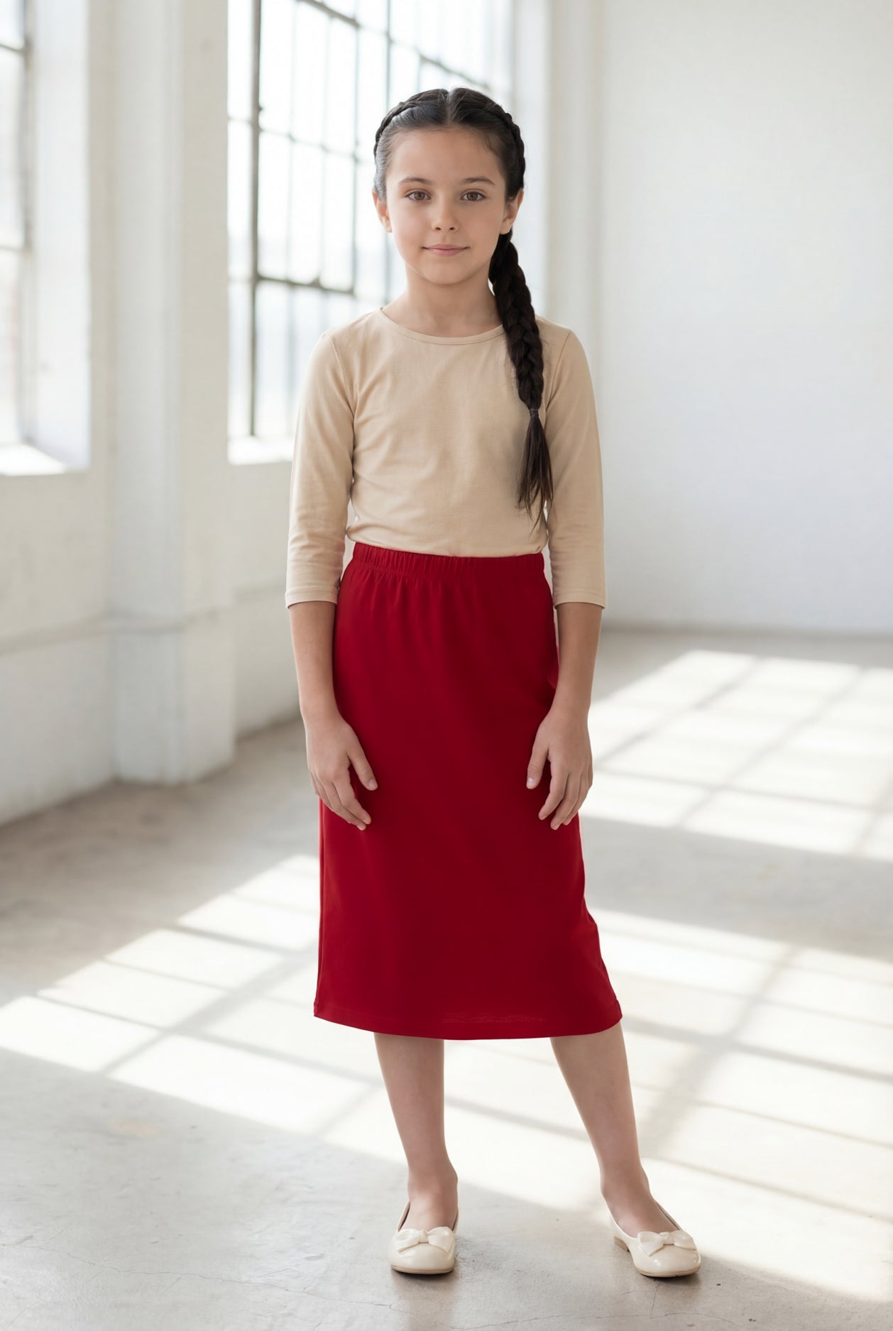 Girl wearing Nuggles® Modest Midi Skirt in Brick Red with a nude essential 3/4 tee in a sun light loft