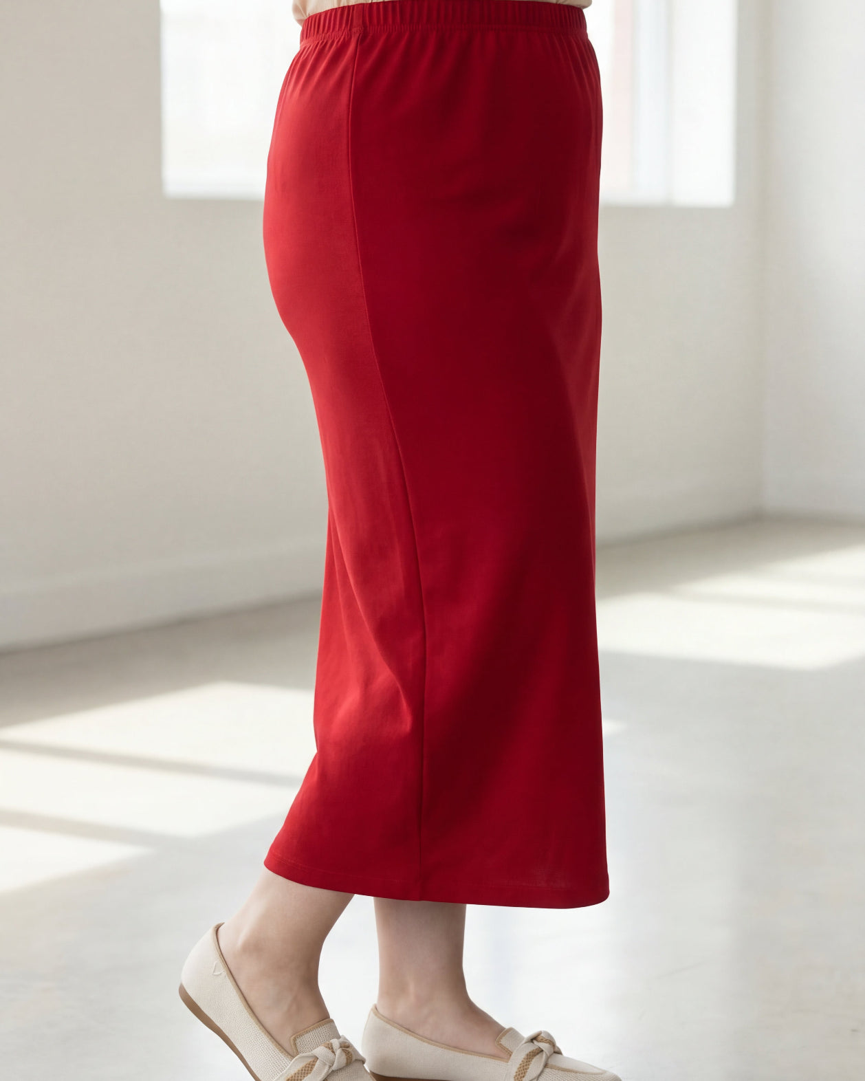 Person wearing a red skirt and white shoes in a bright room