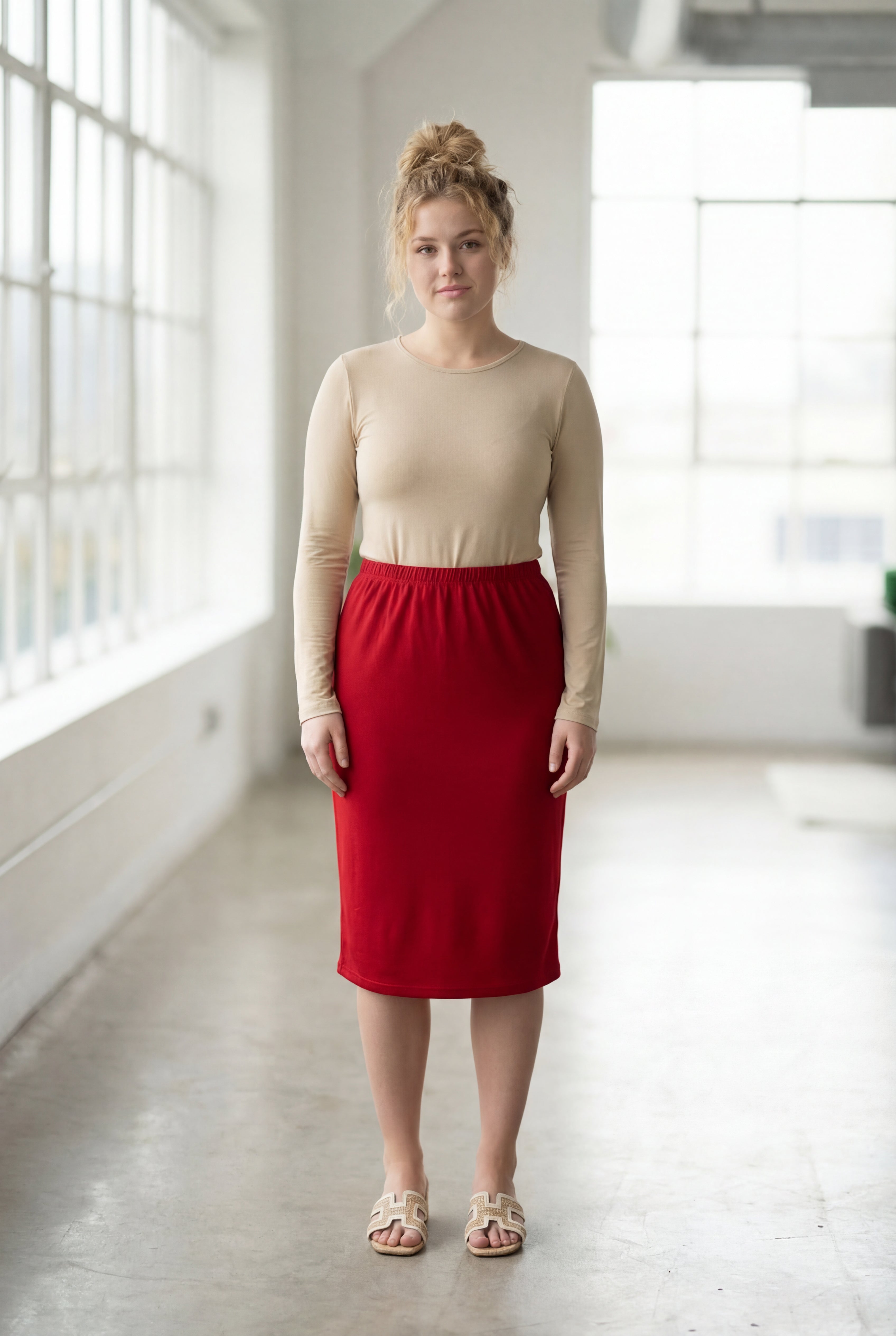 Women wearing a brick red classic 27" midi length skirt with a beige shirt in a sunlight loft.