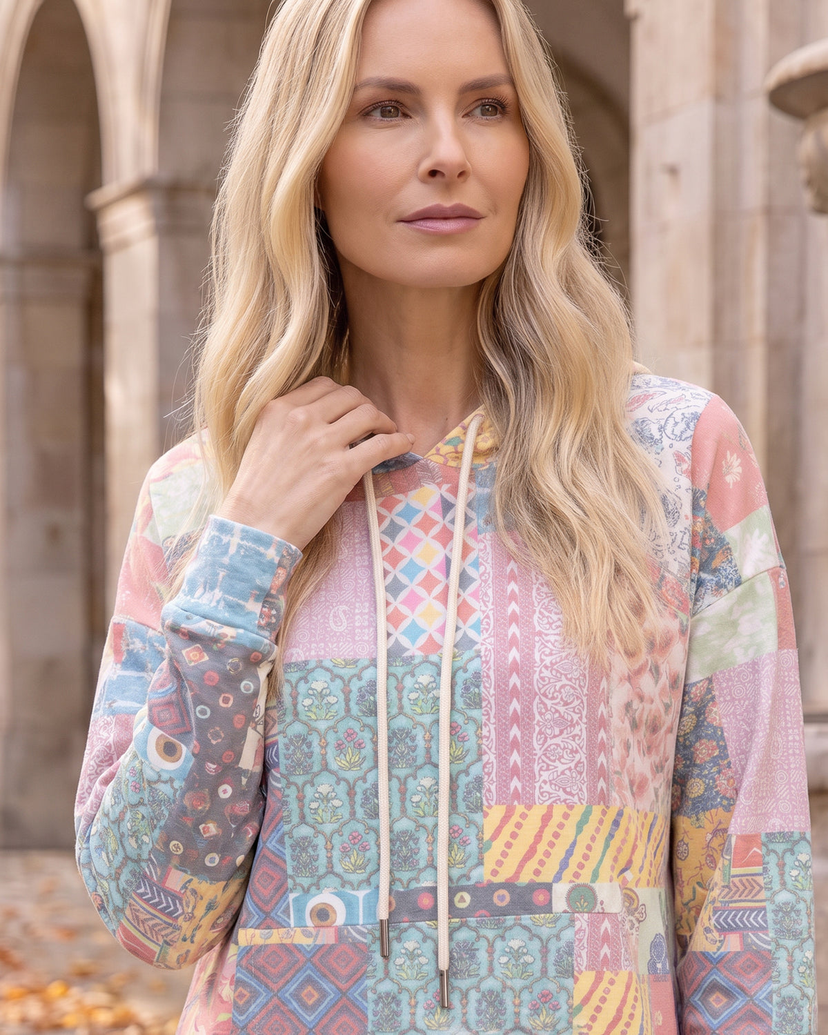 Nuggles® Hoodie Dress in Candy Lane, waist-up crop with a hand on the cream drawstring