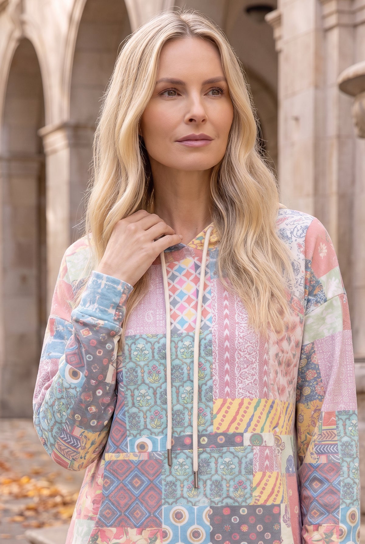 Nuggles® Hoodie Dress in Candy Lane, waist-up crop with a hand on the cream drawstring