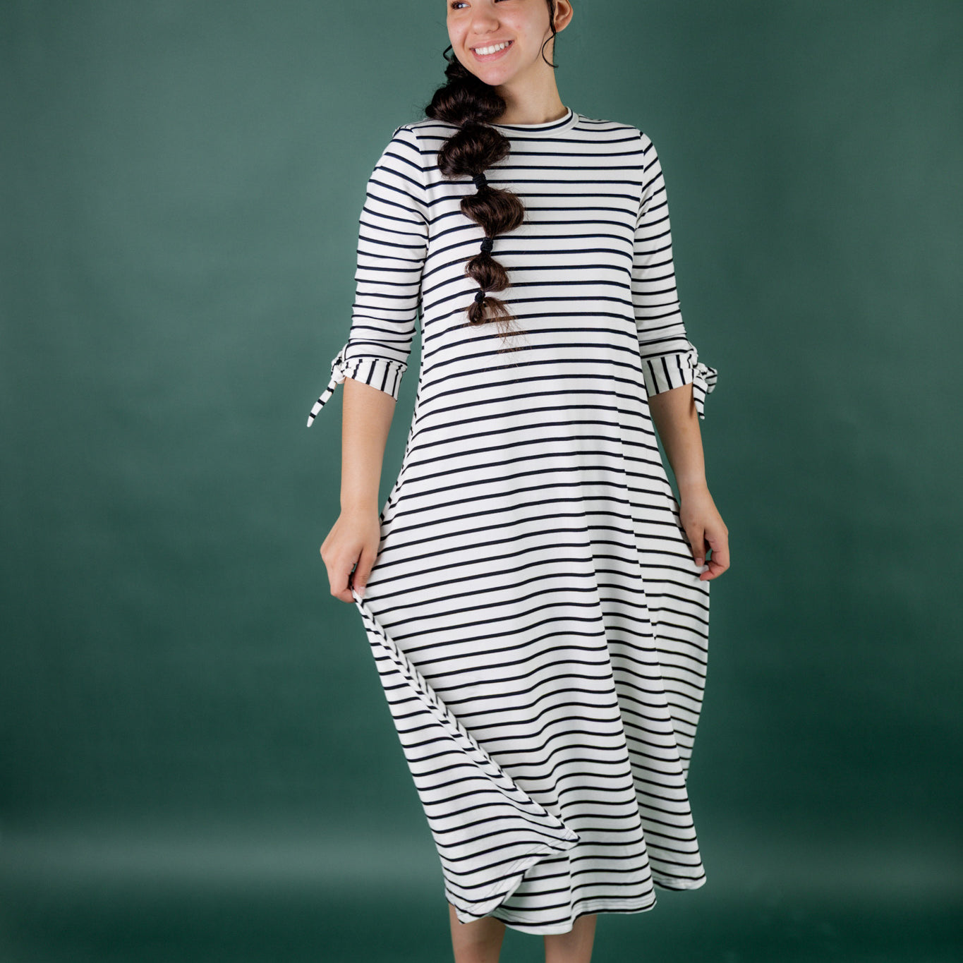 Model wearing the Nuggles® Gracie Dress, a modest A-line midi dress with ¾ sleeves and tie accents, made from soft knit fabric.