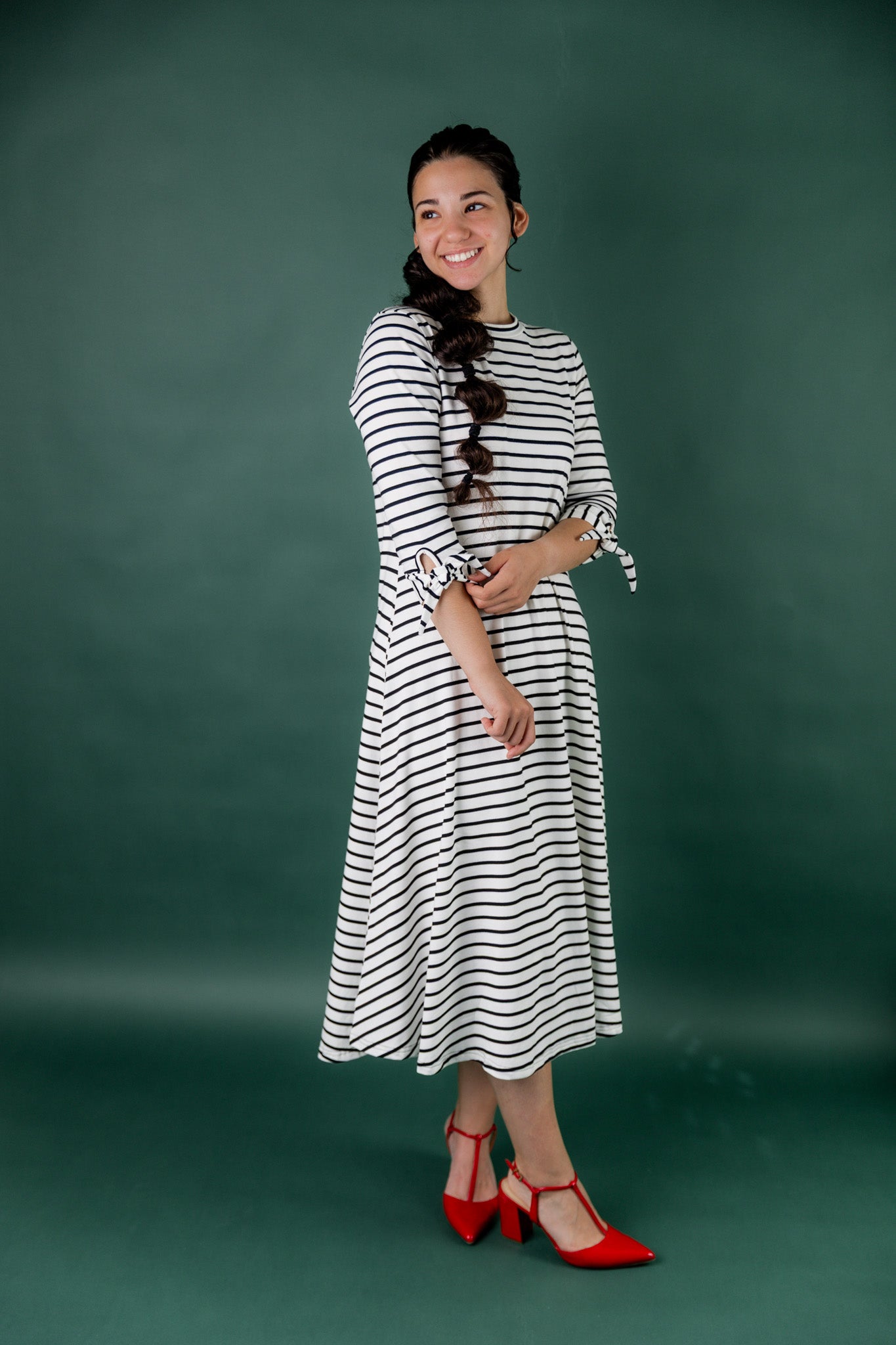 Model wearing the Nuggles® Gracie Dress, a modest A-line midi dress with ¾ sleeves and tie accents, made from soft knit fabric.