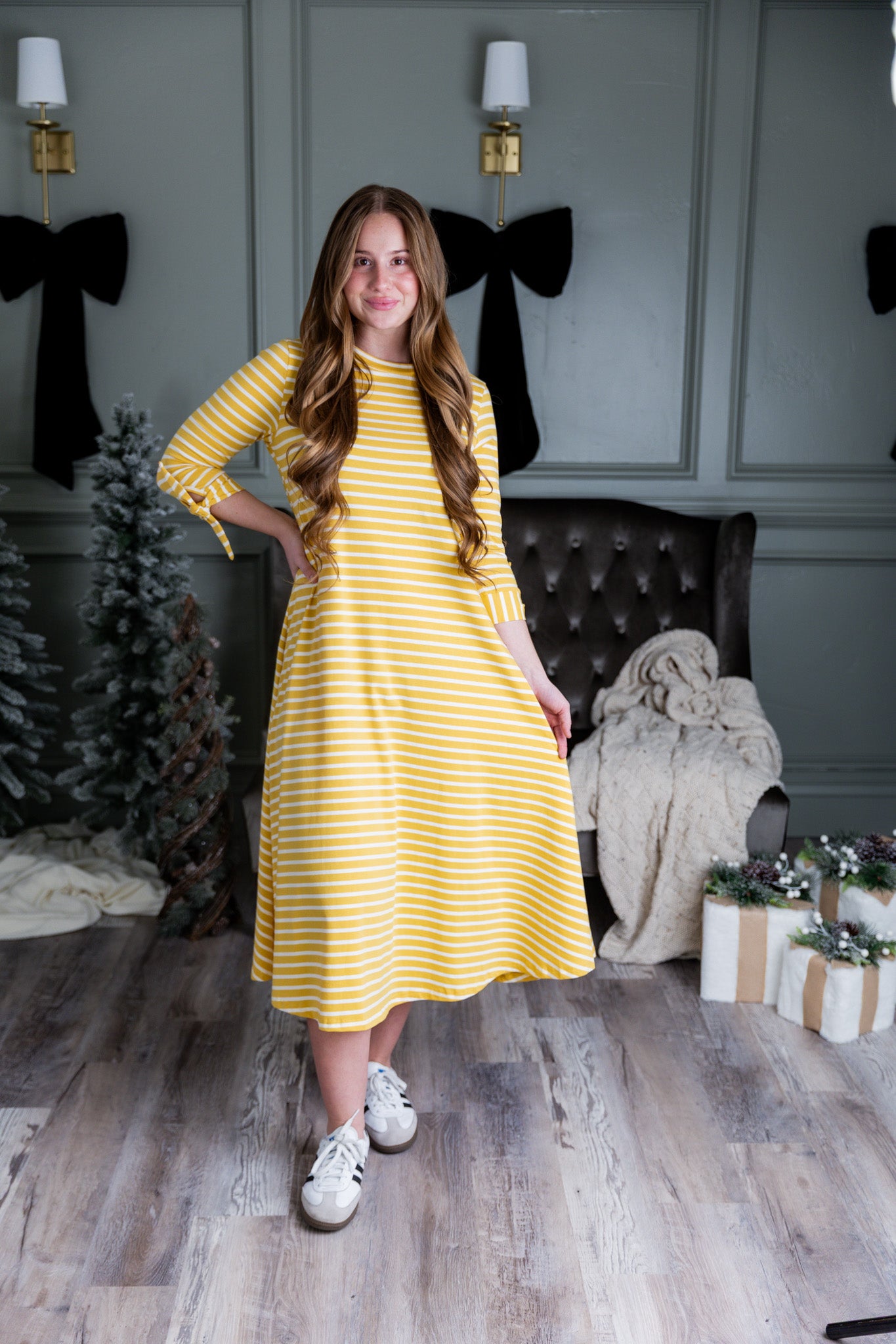 Model wearing the Nuggles® Gracie Dress, a modest A-line midi dress with ¾ sleeves and tie accents, made from soft knit fabric.