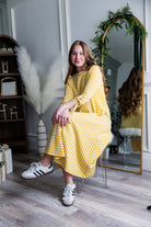 Model wearing the Nuggles® Gracie Dress, a modest A-line midi dress with ¾ sleeves and tie accents, made from soft knit fabric.