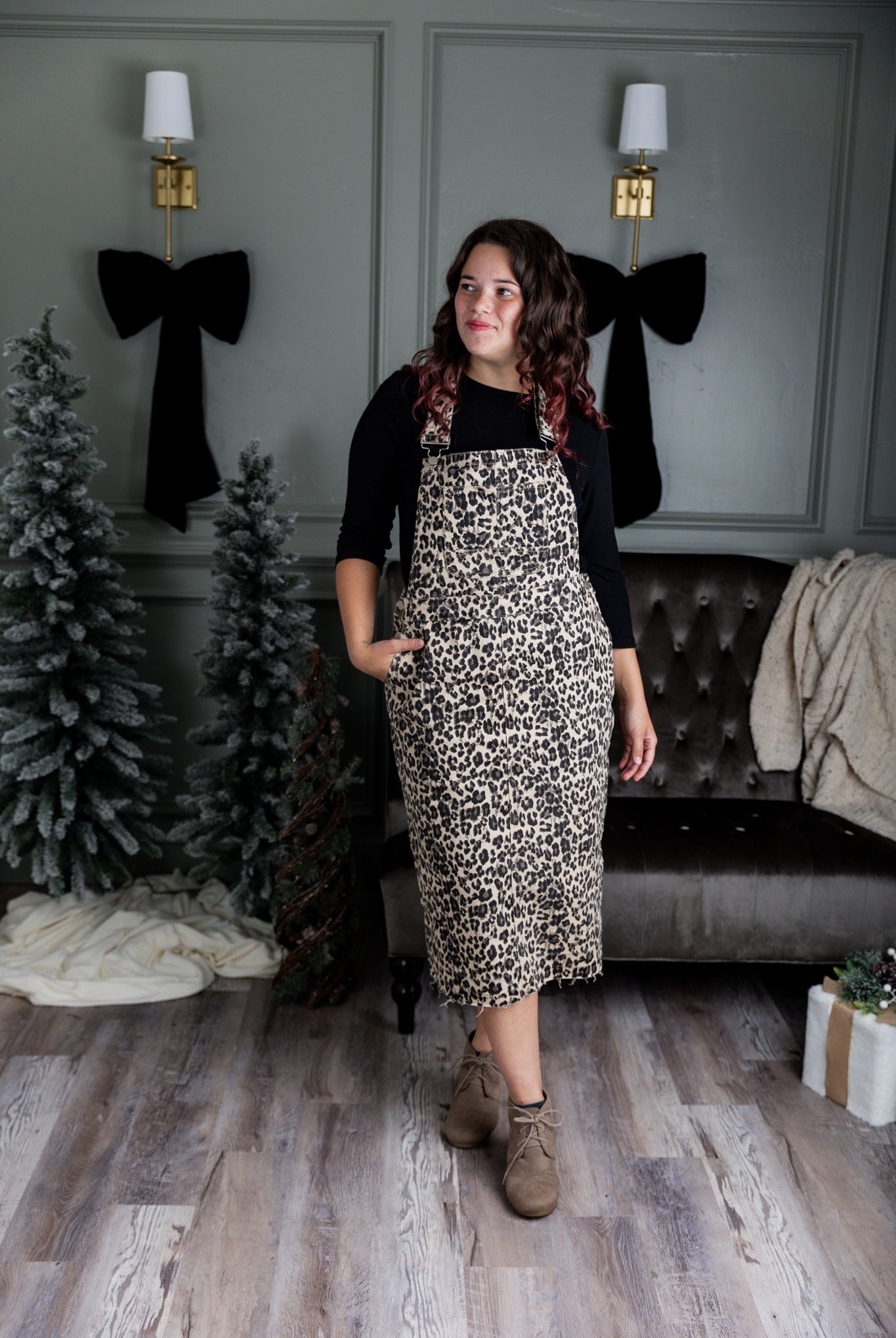 Model wearing a 'NUGGLES® modest leopard denim overall dress with front pocket and raw hem.