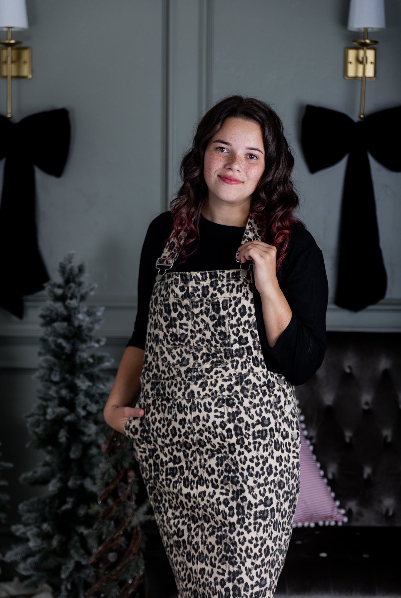 Model wearing a 'NUGGLES® modest leopard denim overall dress with front pocket and raw hem.