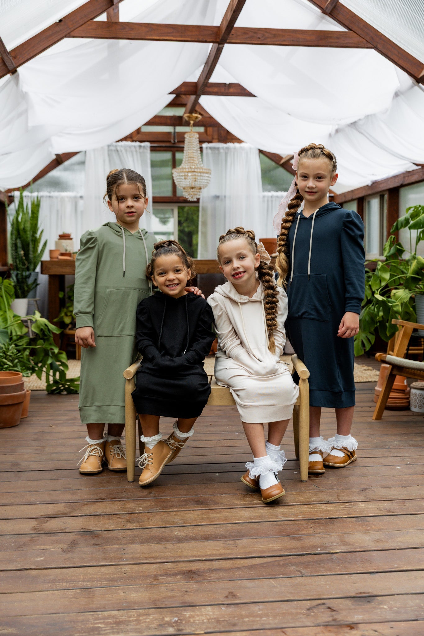 Young girl wearing Nuggles® Zoelle Dress in solid color, modest hoodie dress with puff sleeves.