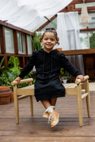 Young girl wearing Nuggles® Zoelle Dress in solid color, modest hoodie dress with puff sleeves.
