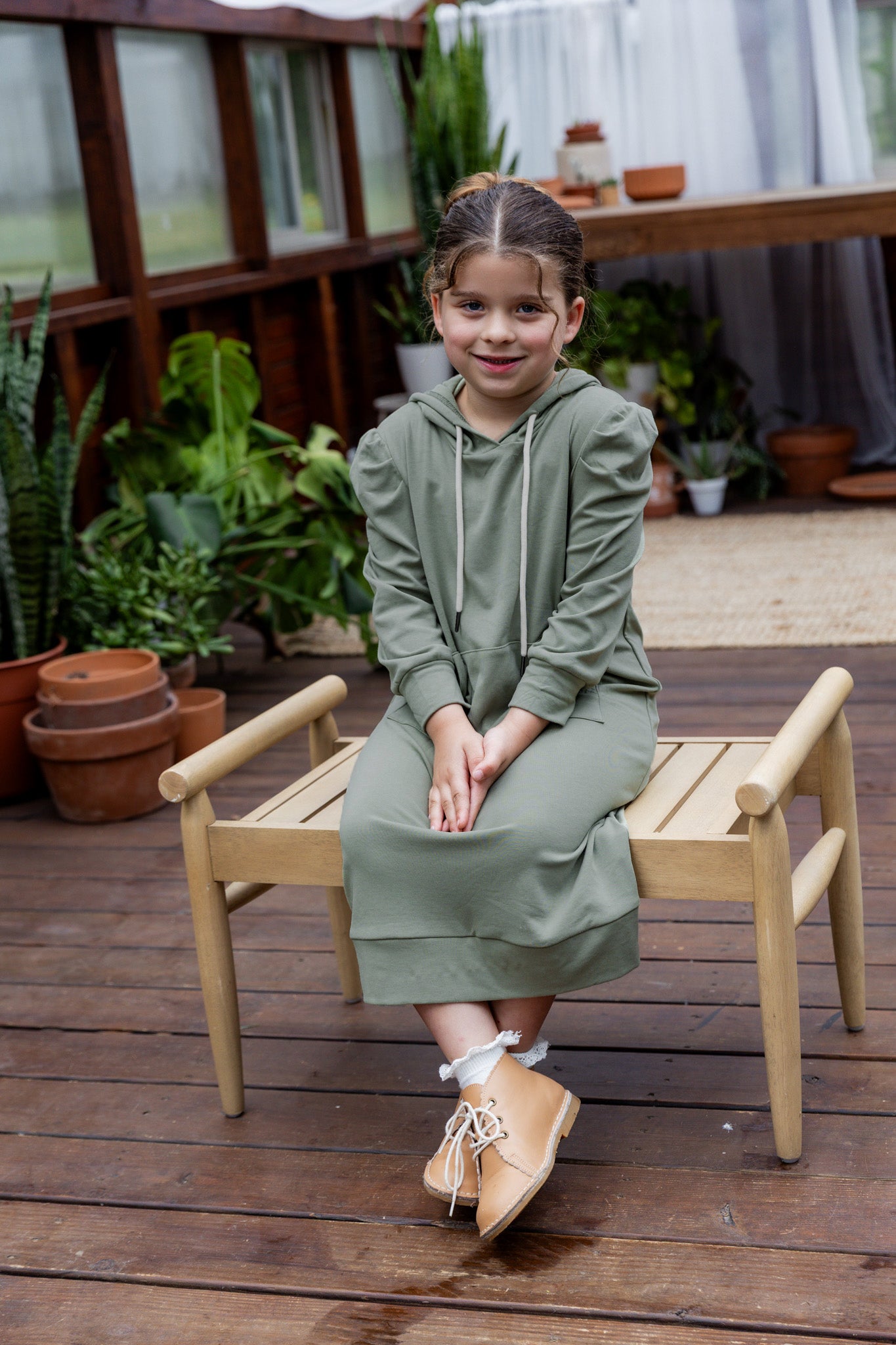 Young girl wearing Nuggles® Zoelle Dress in solid color, modest hoodie dress with puff sleeves.