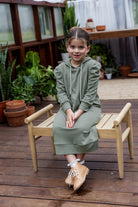 Young girl wearing Nuggles® Zoelle Dress in solid color, modest hoodie dress with puff sleeves.