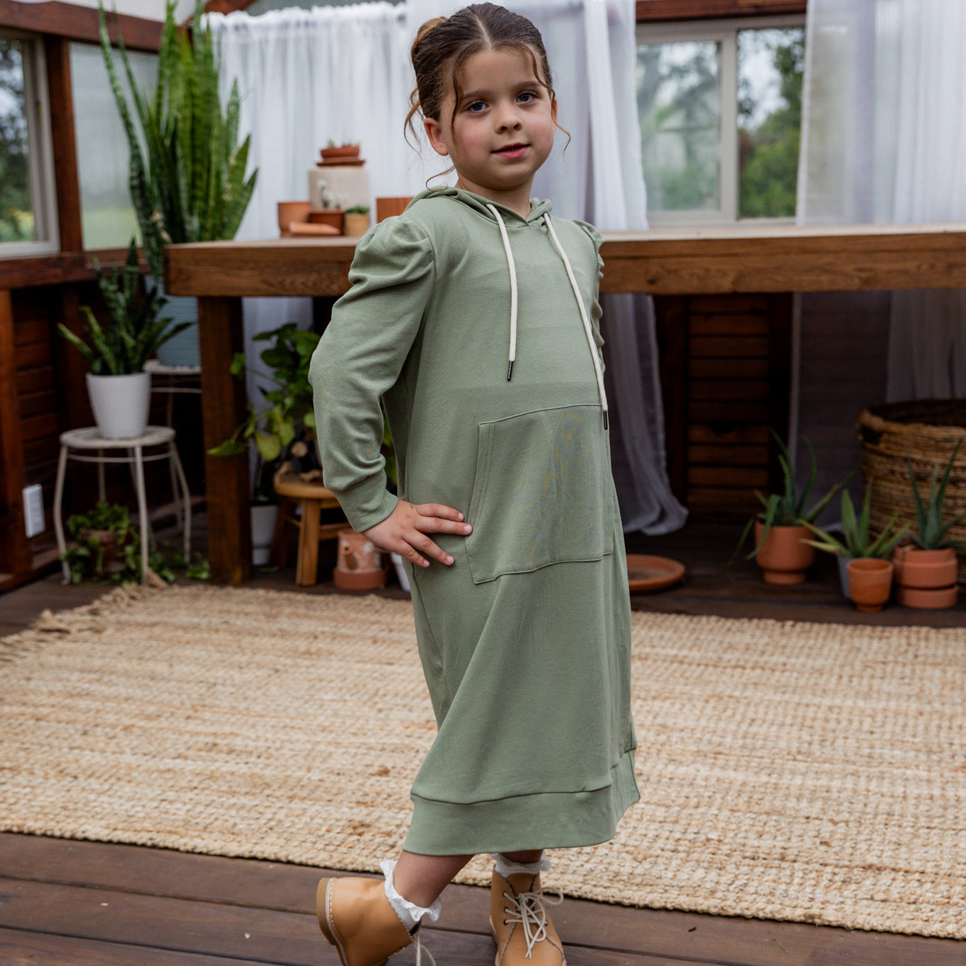 Young girl wearing Nuggles® Zoelle Dress in solid color, modest hoodie dress with puff sleeves.
